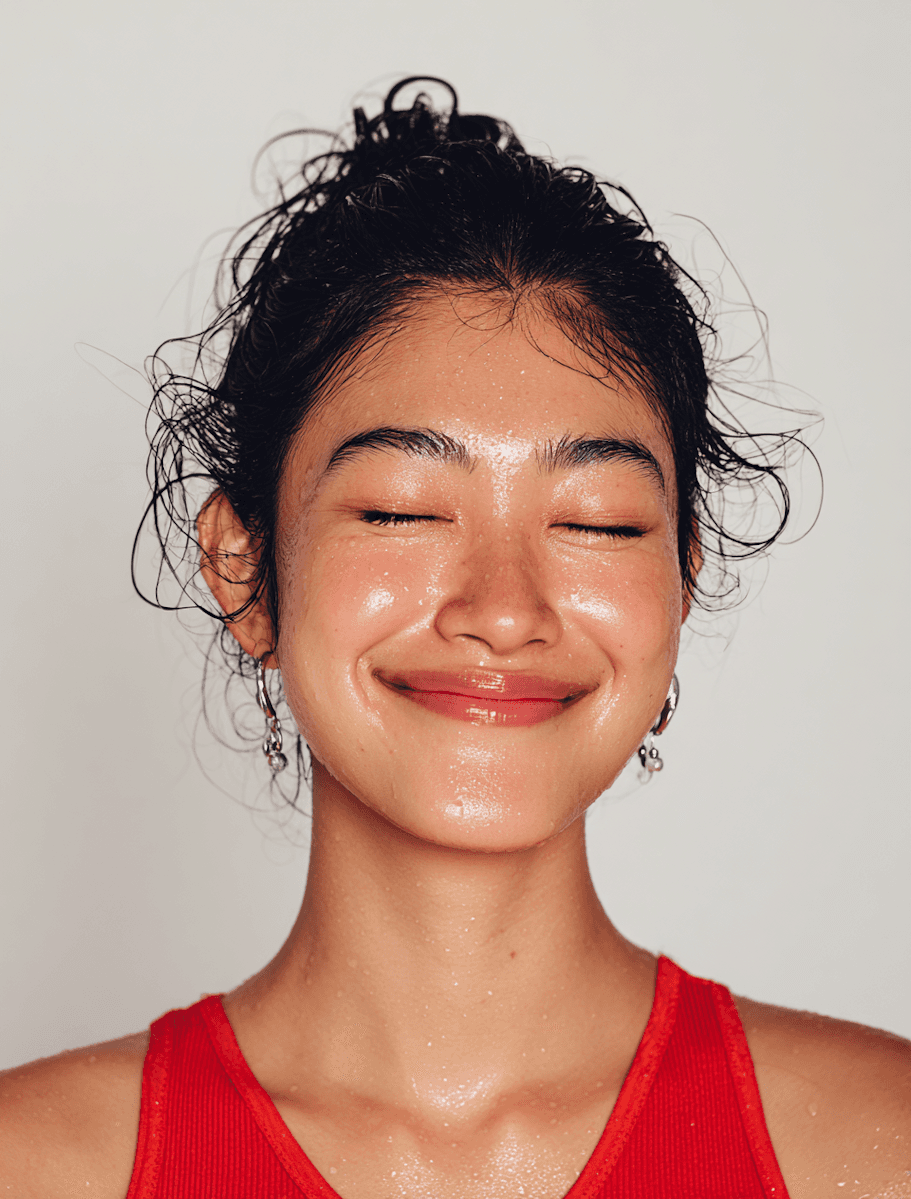 Close-up of a woman with eyes closed and a calm smile, glowing skin