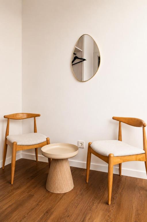 Casa Jazmín Granada: Two wood chairs and a small round table beneath a wall mirror