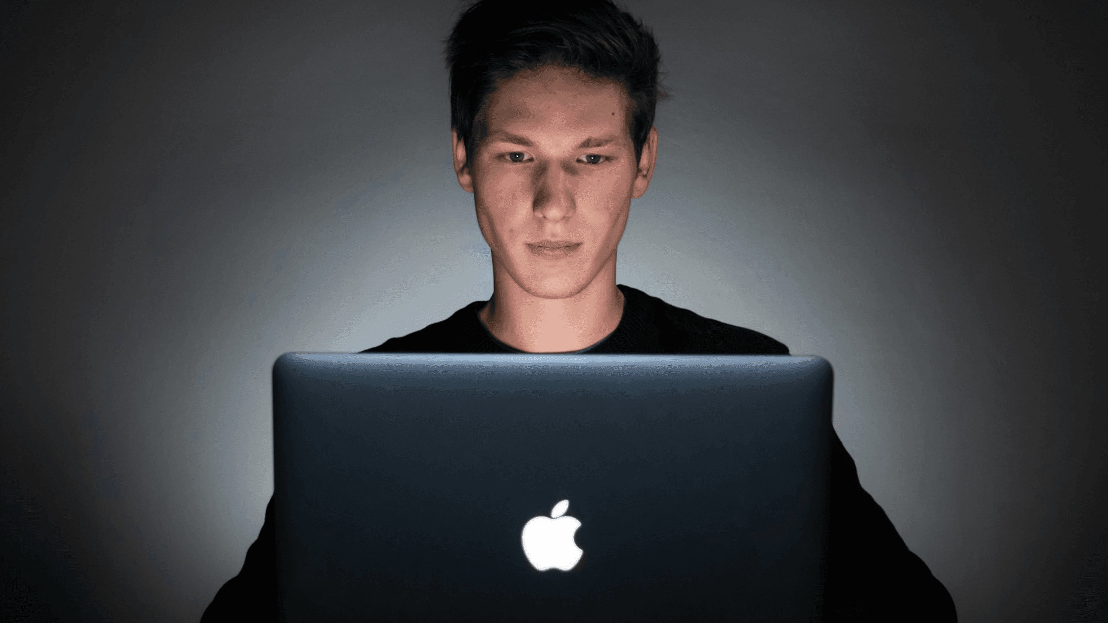 A man sitting behind a laptop working