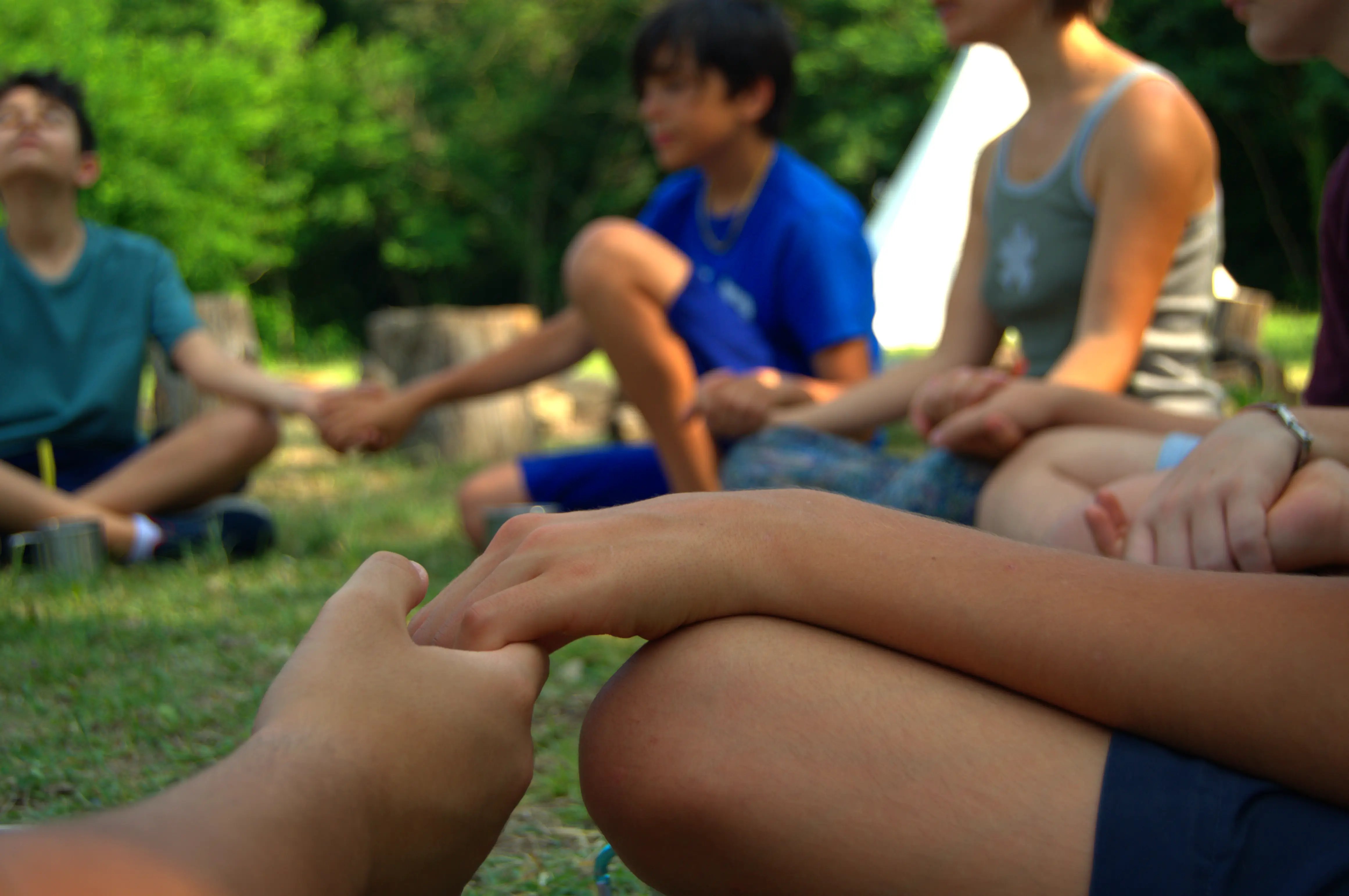 Ragazzi in cerchio con mani unite durante campo estivo, sostieni i progetti di outdoor education, campi avventura e educazione ambientale per le scuole