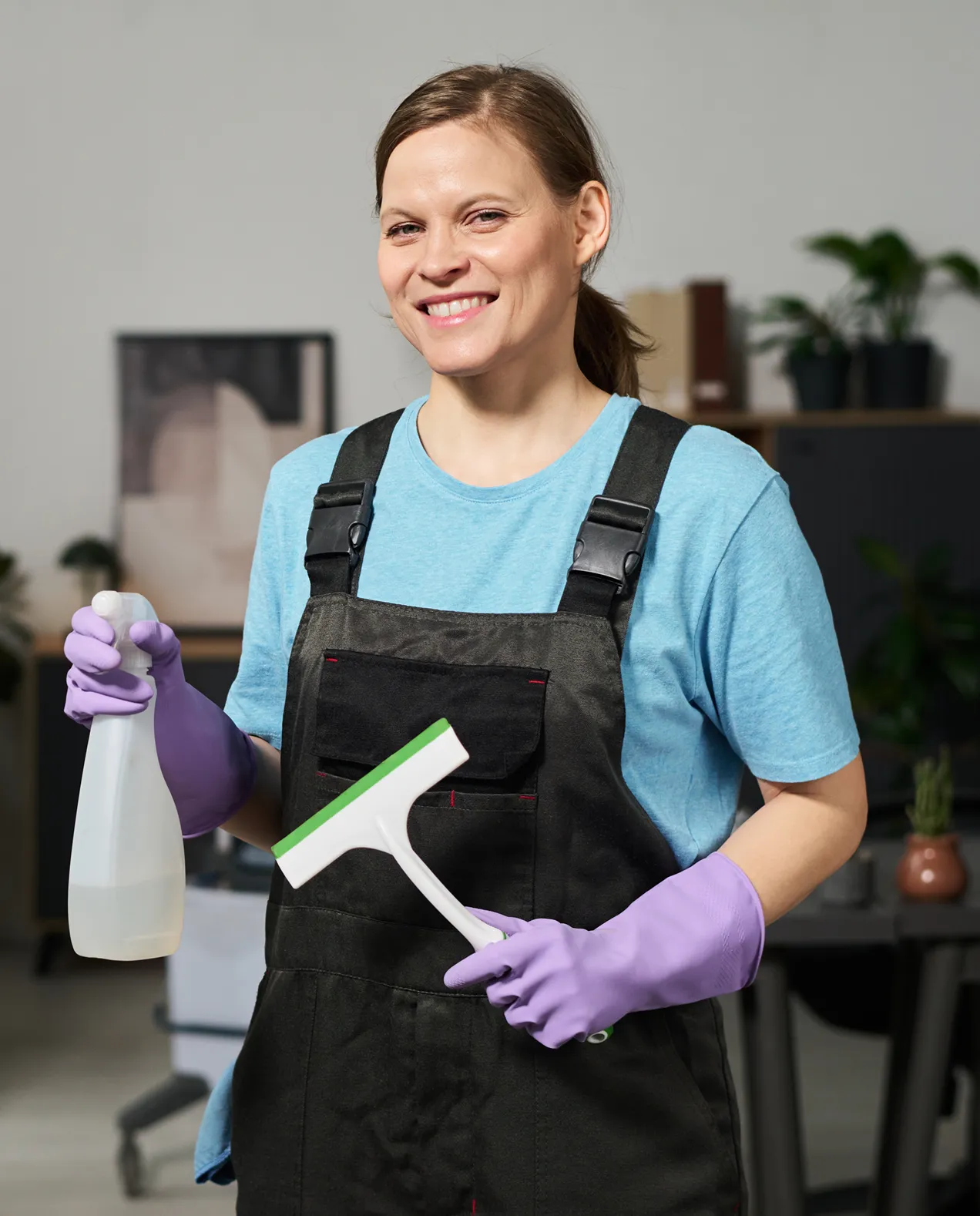 Team Lead Mariya Lee holding a window squeegee and spray bottle, representing 6 years of leadership in professional home cleaning visits.