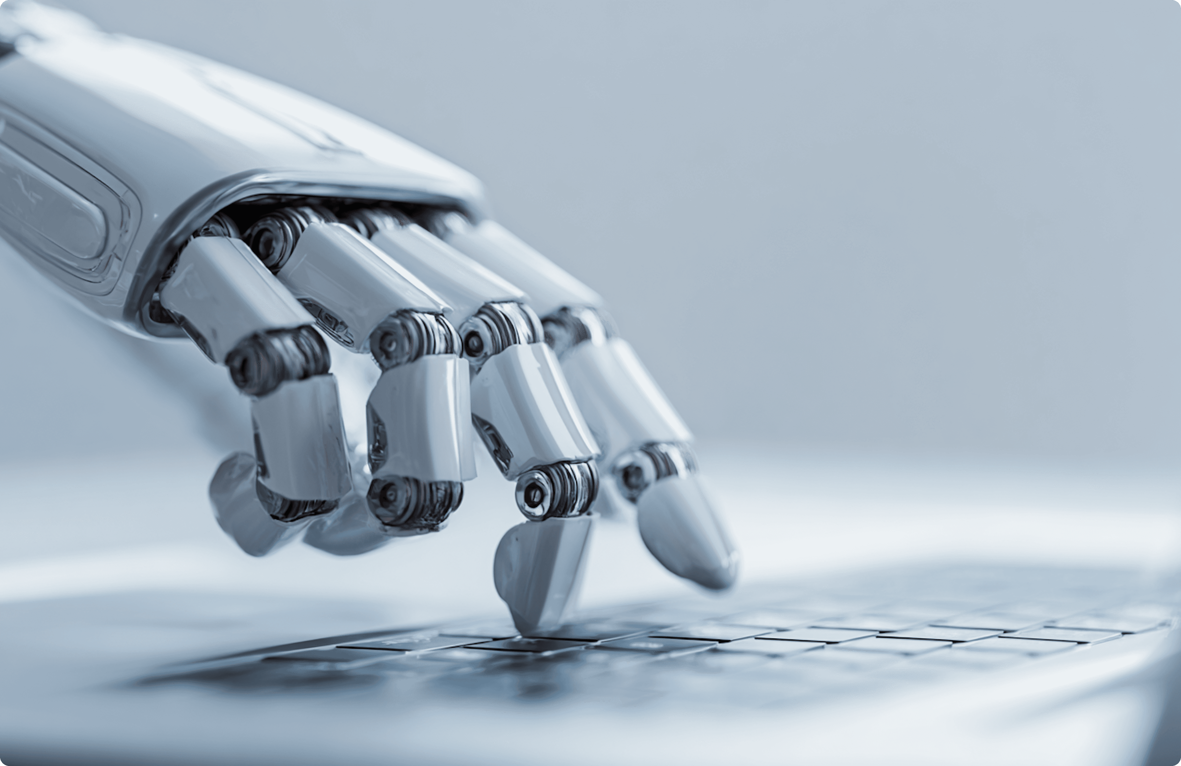 A close-up of a white robot hand typing on a laptop keyboard.