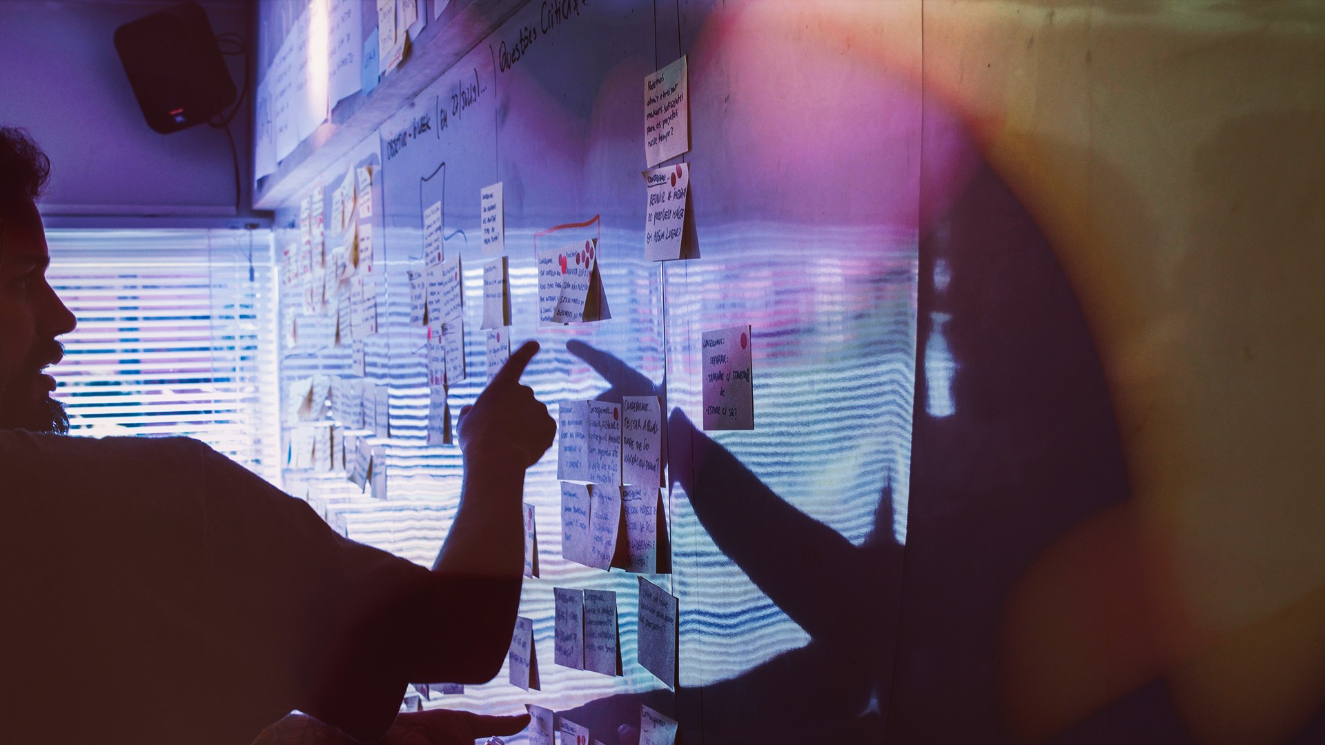 A person points towards sticky notes attached to a wall