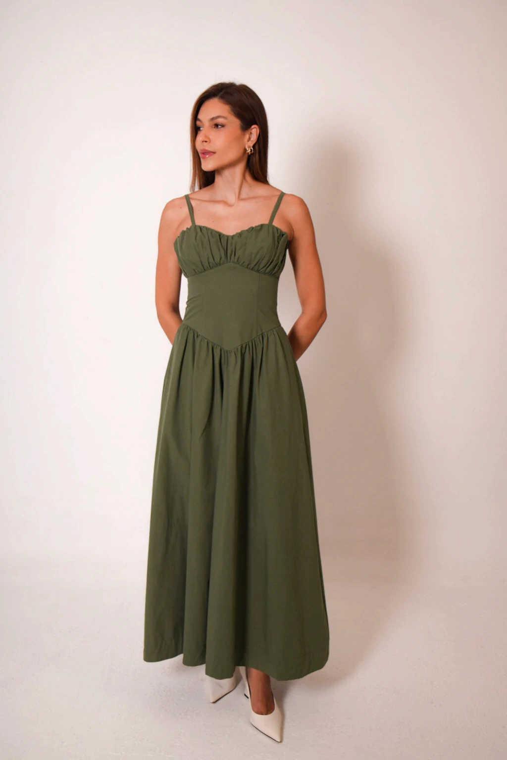 Vestido Carla verde na altura do quadril, com as maos nos bolsos laterais