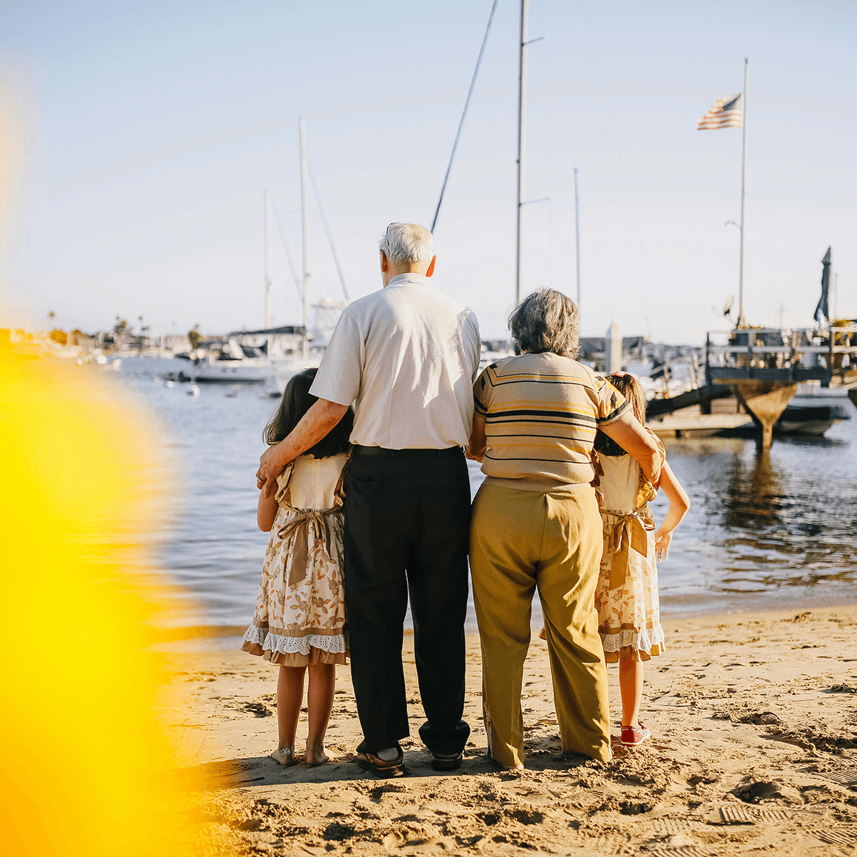 Back view of an elderly couple and their grandchildren at the beach