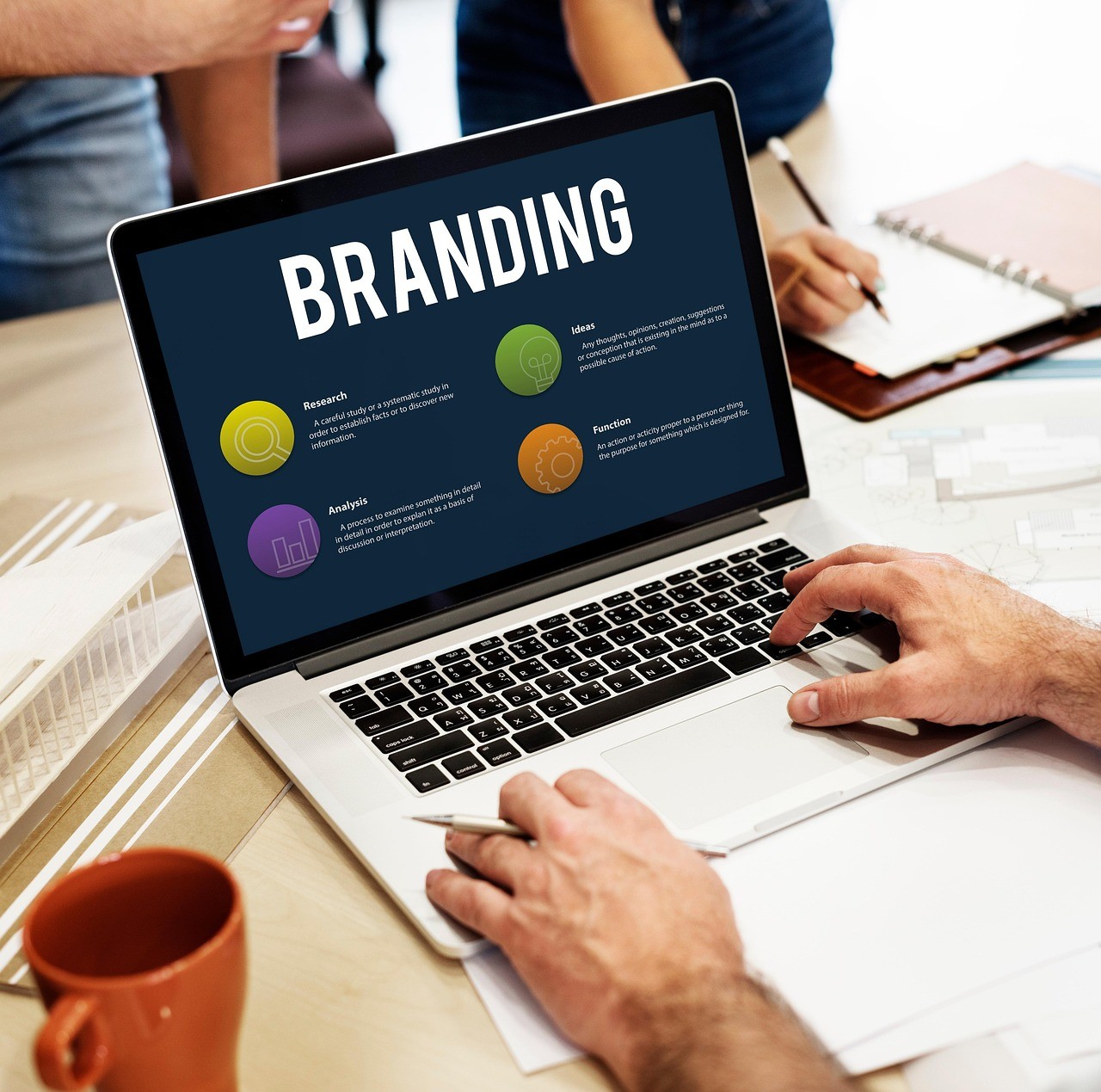 Laptop screen showing branding concept with hands typing on keyboard