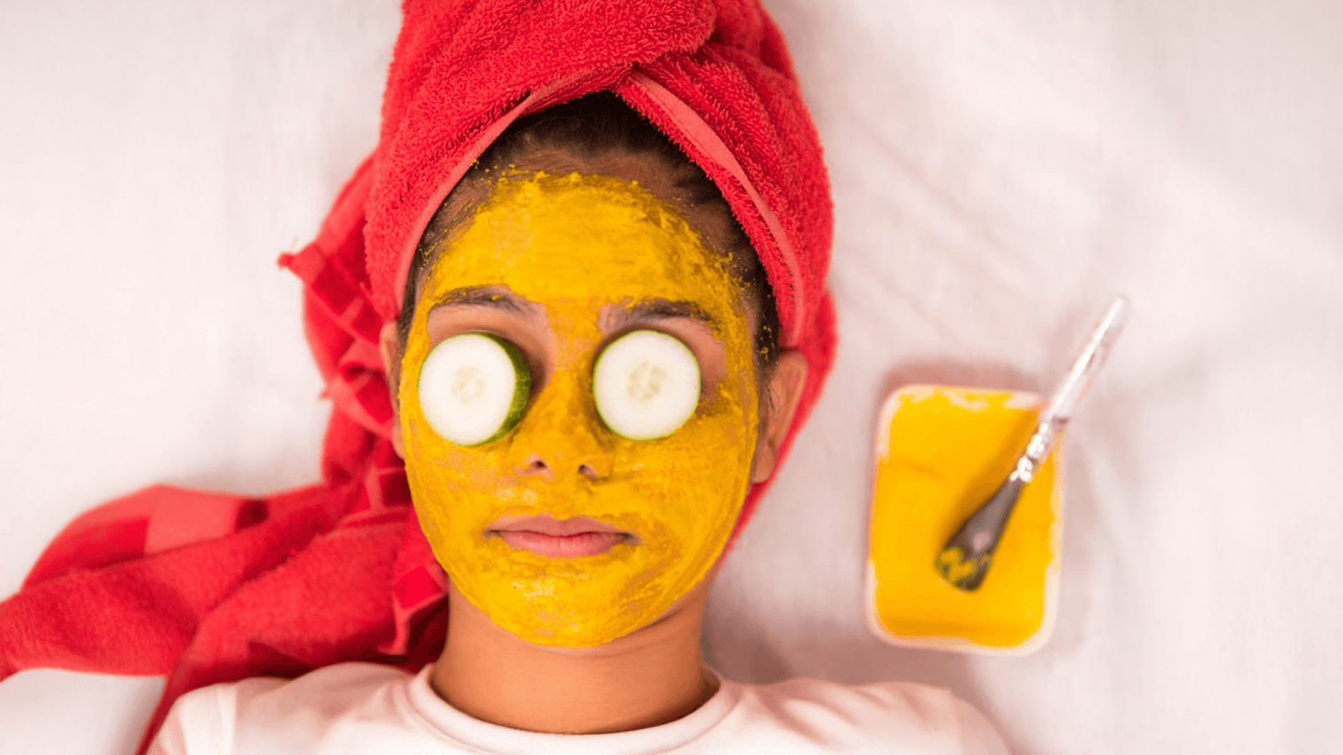 Woman with turmeric face mask and cucumber slices on eyes