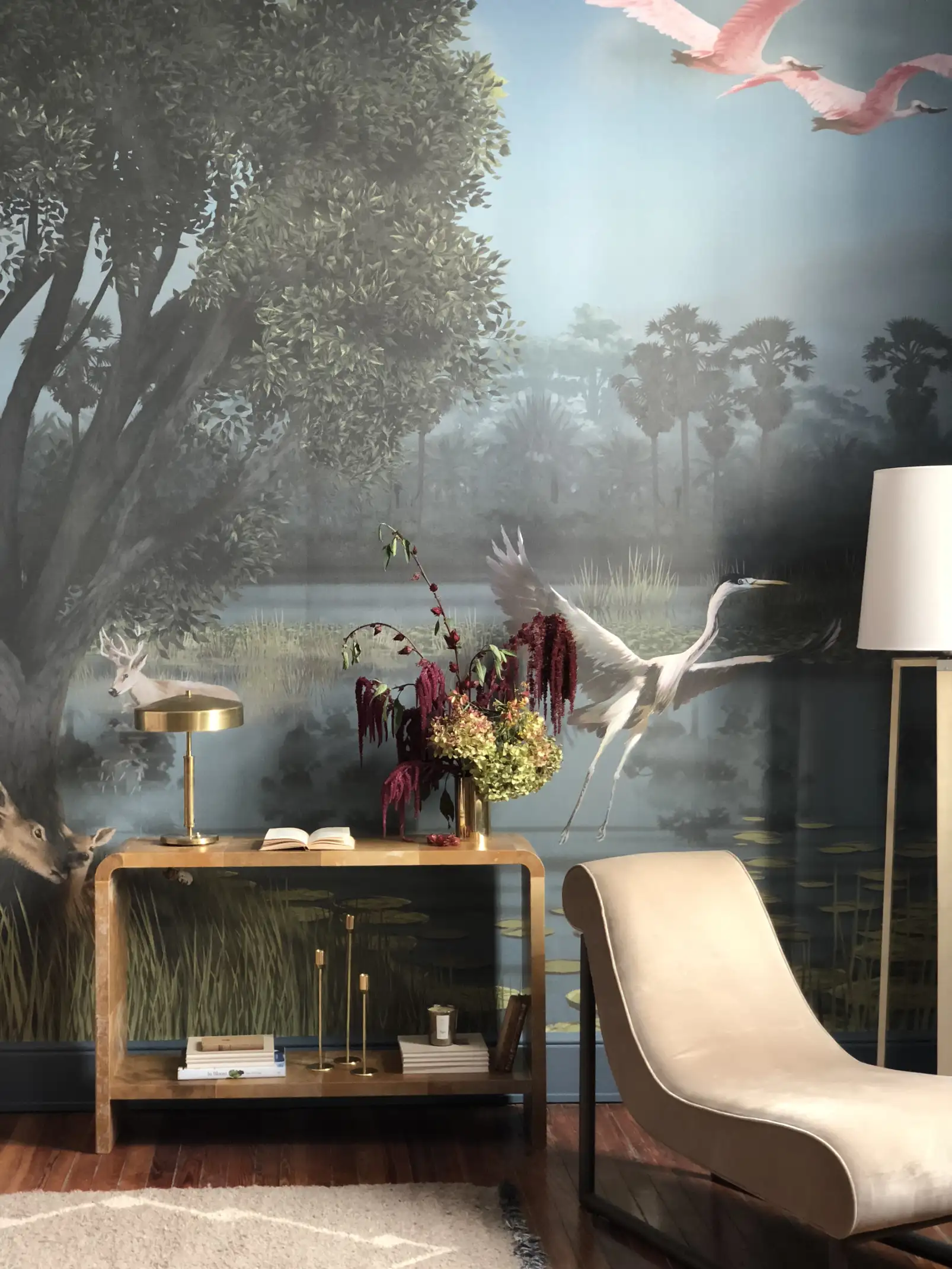 Interior cálido con mural natural, sillón moderno y jarrón floral sobre consola para inspiración en diseño de interiores sofisticado.