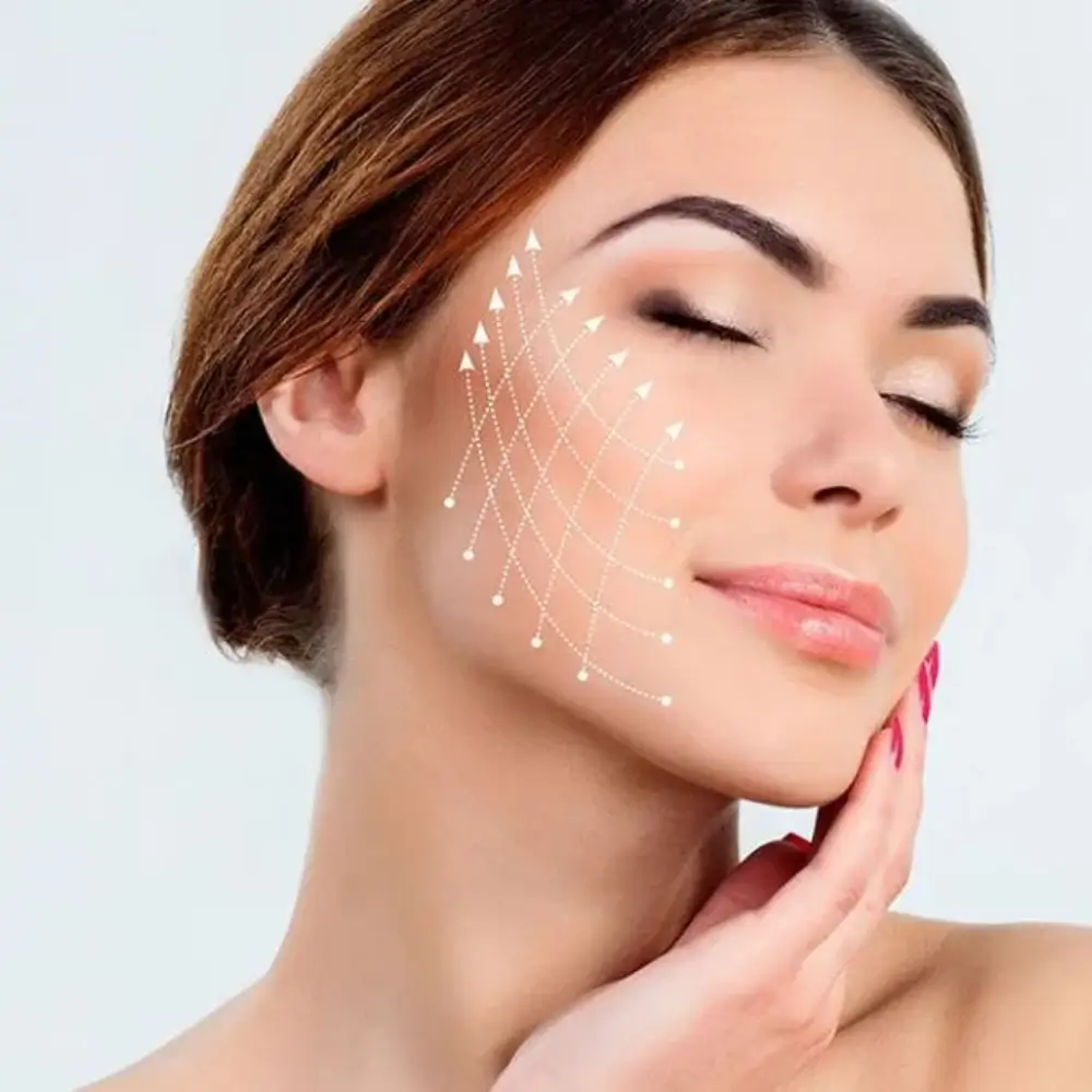 A woman lying down with a towel wrapped around her head, her face glowing with facial oil. She has a peaceful expression, enjoying a skincare treatment.