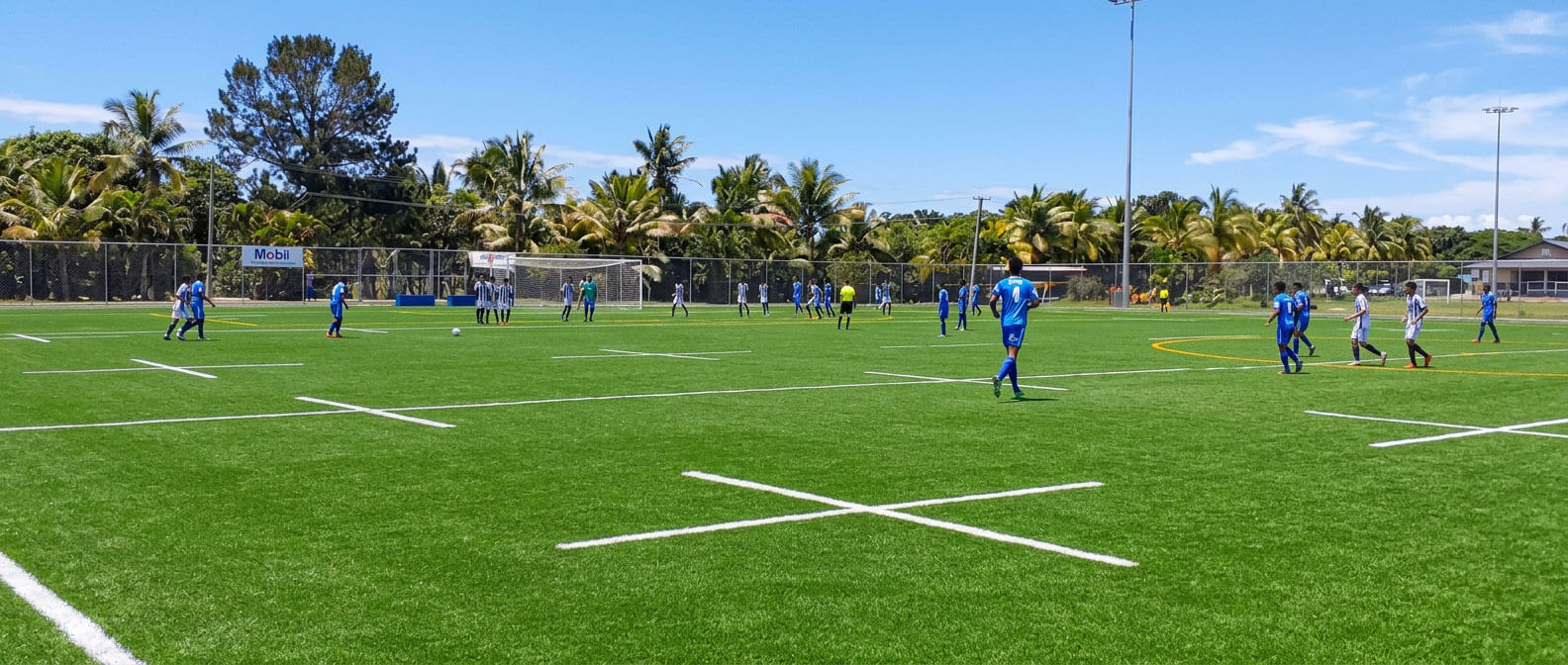 Soccer players on a green artificial pitch at Uprising Beach Resort, ideal for sports teams and training.