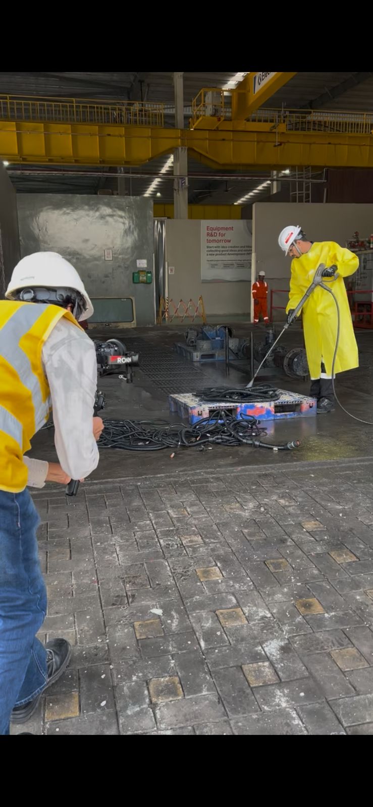 Close-up portrait of a person wearing a gray insulated hooded jacket with the hood up, showing their face framed by the hood against a light background.