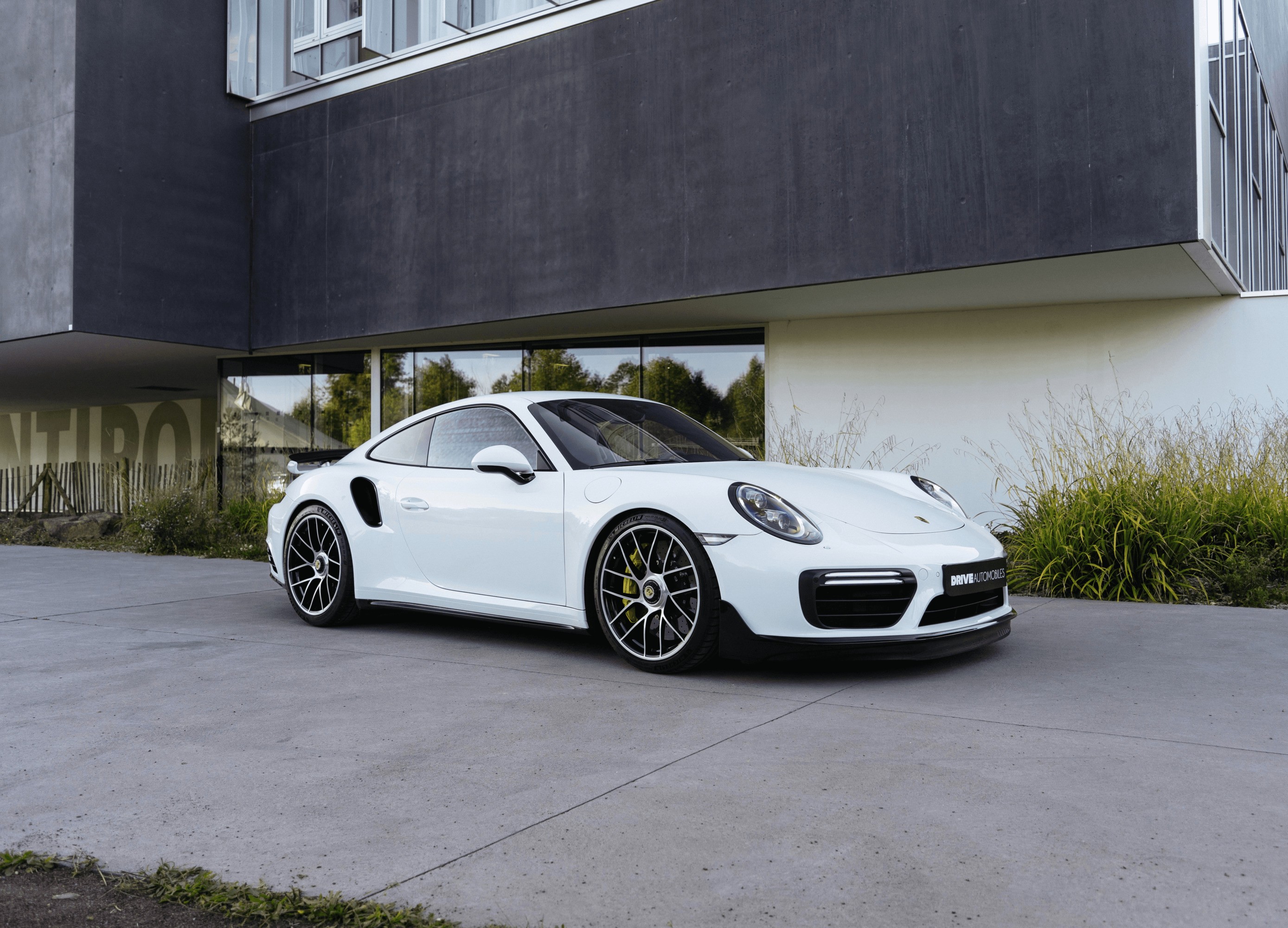 a white porsche parked in front of a building