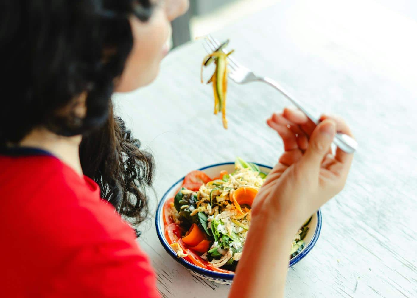 Woman in red shirt eating a salad