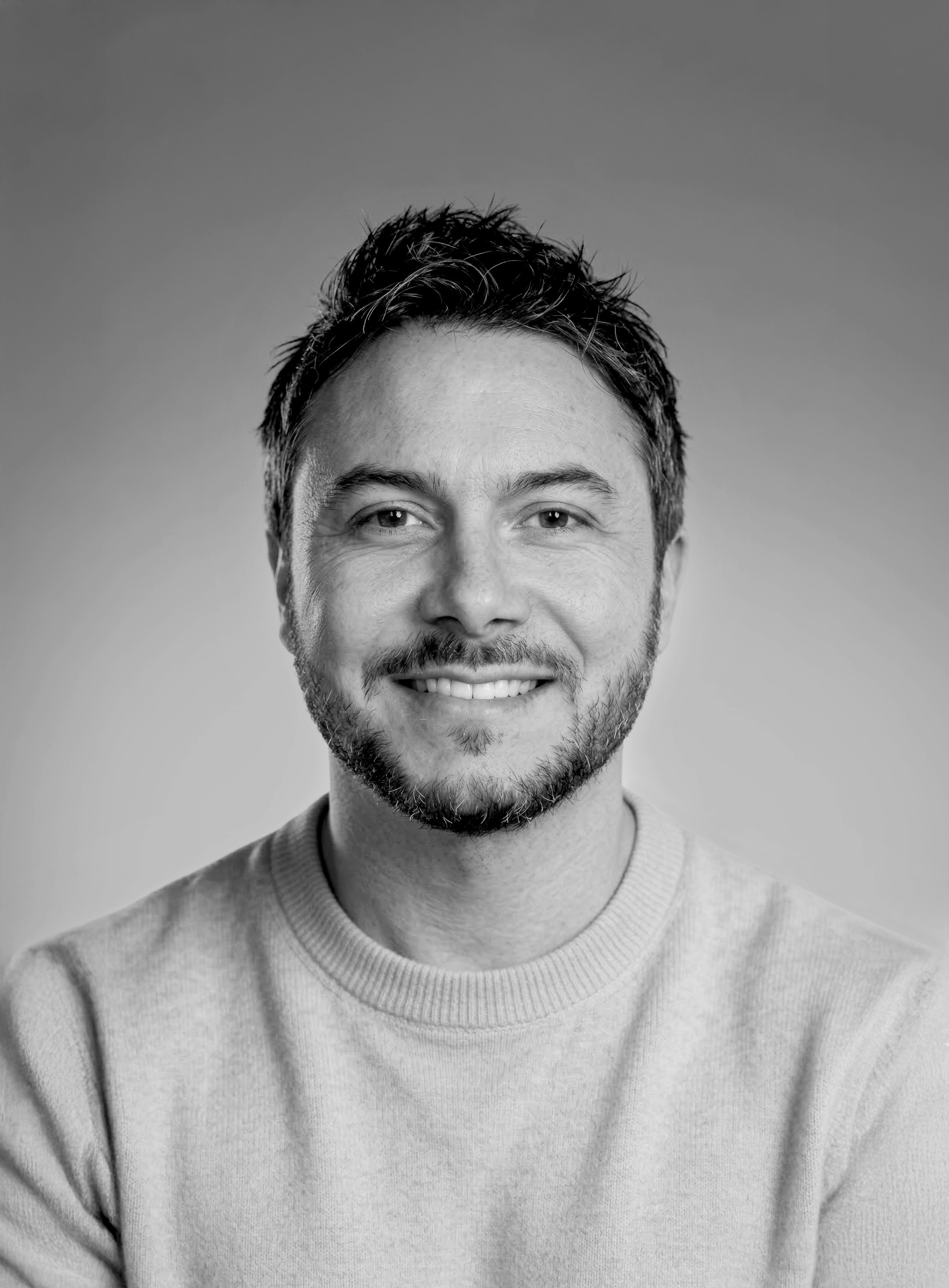 Smiling man in a sweater, black and white portrait.