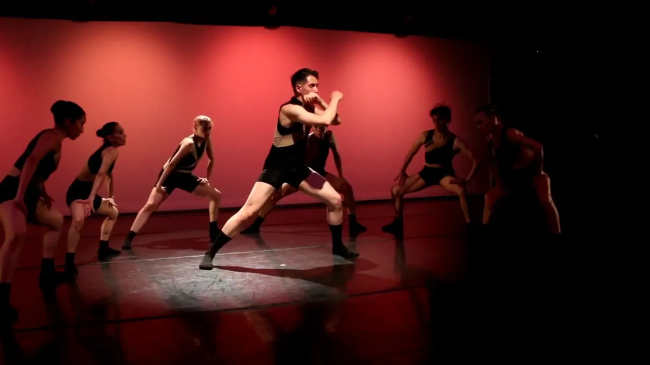 Dancers moving across a red-lit stage