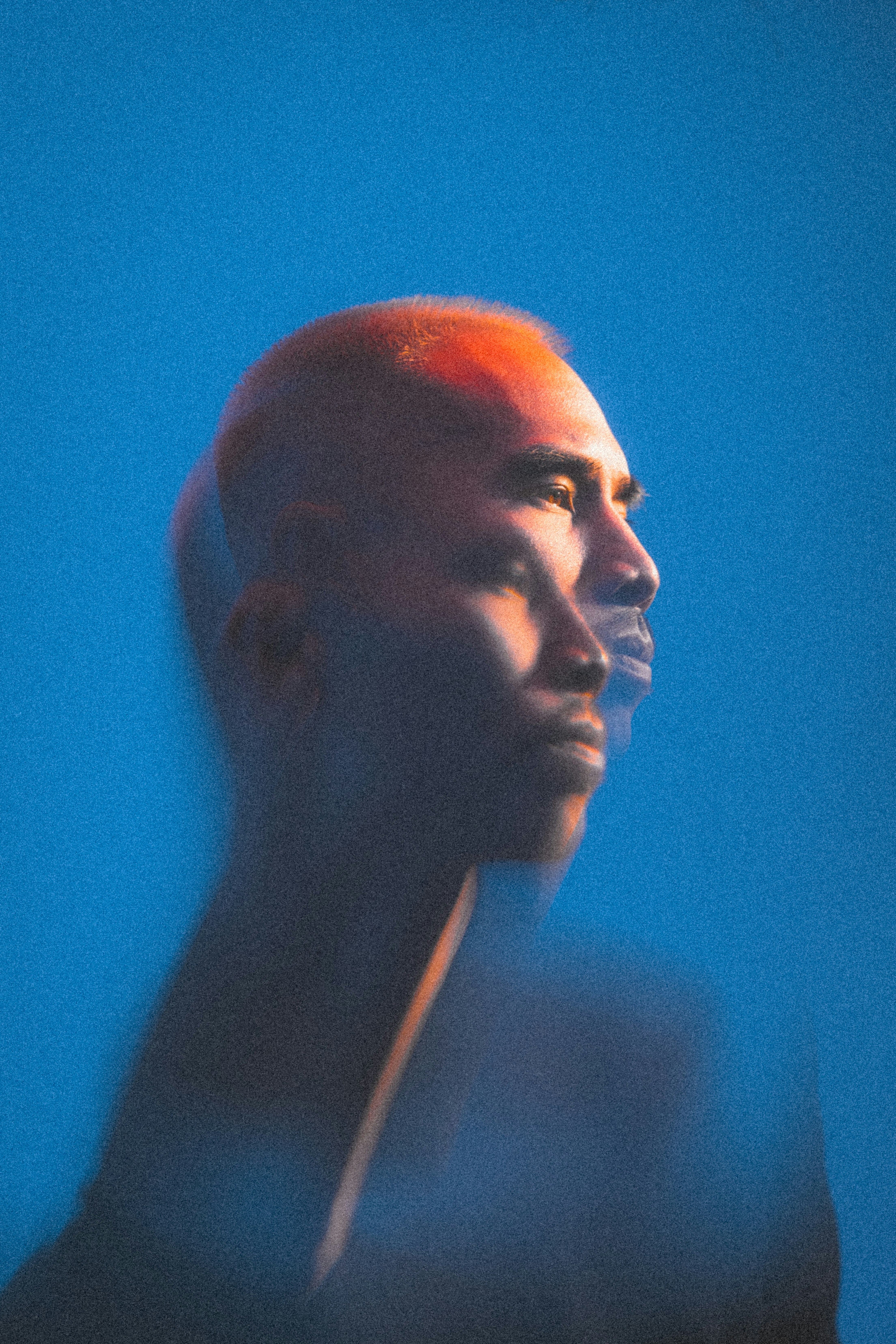 Man with orange hair in profile against blue background.