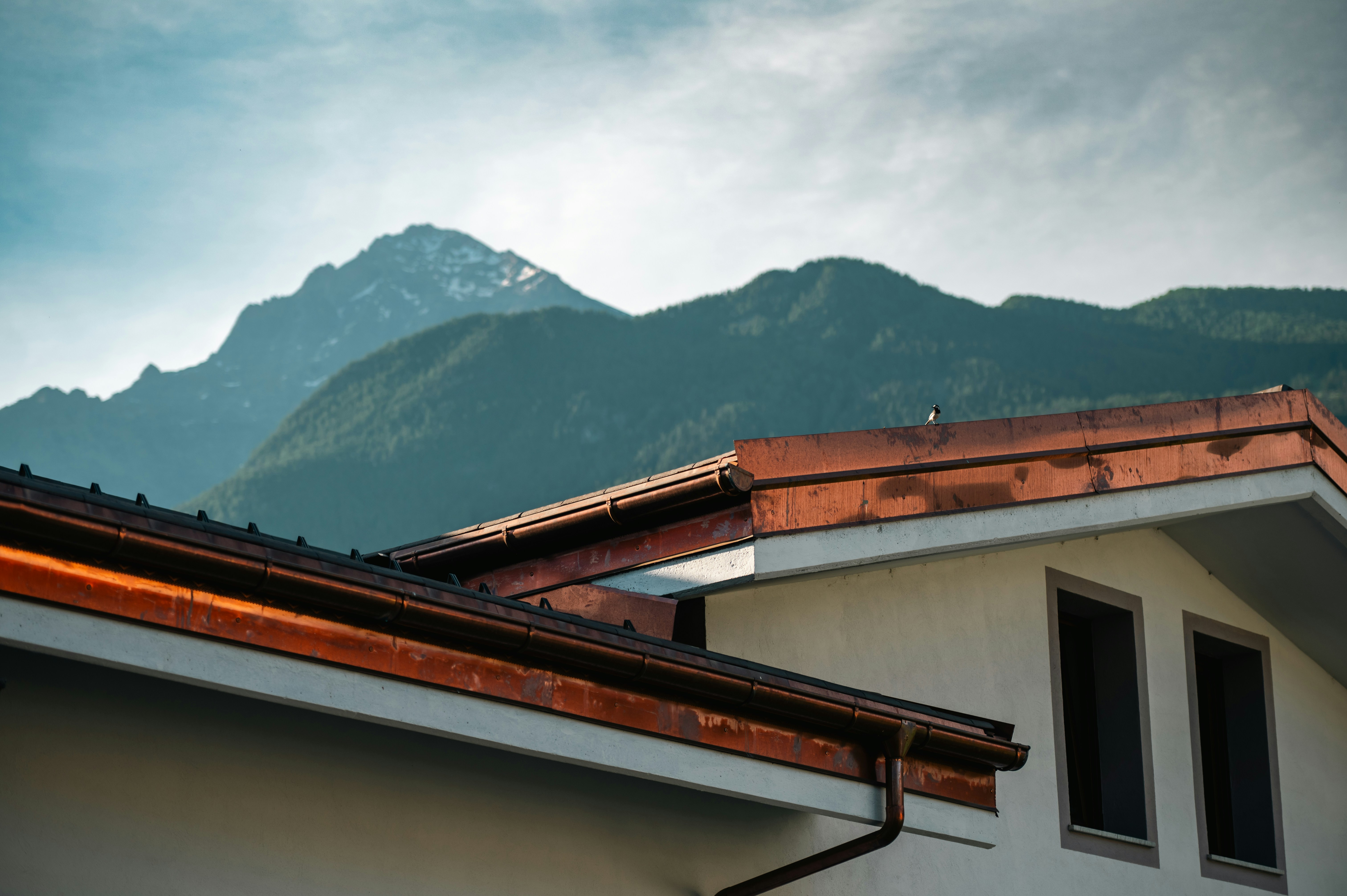 Kupfer-Dachrinne und Blechverkleidung am Dachrand vor Bergpanorama