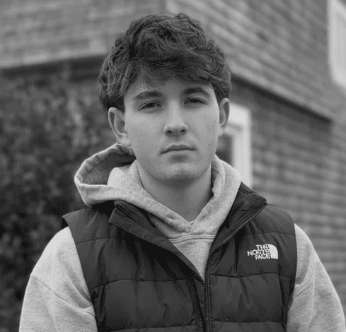 Portrait of a woman with straight long hair, in a dark t-shirt, set against a neutral backdrop.