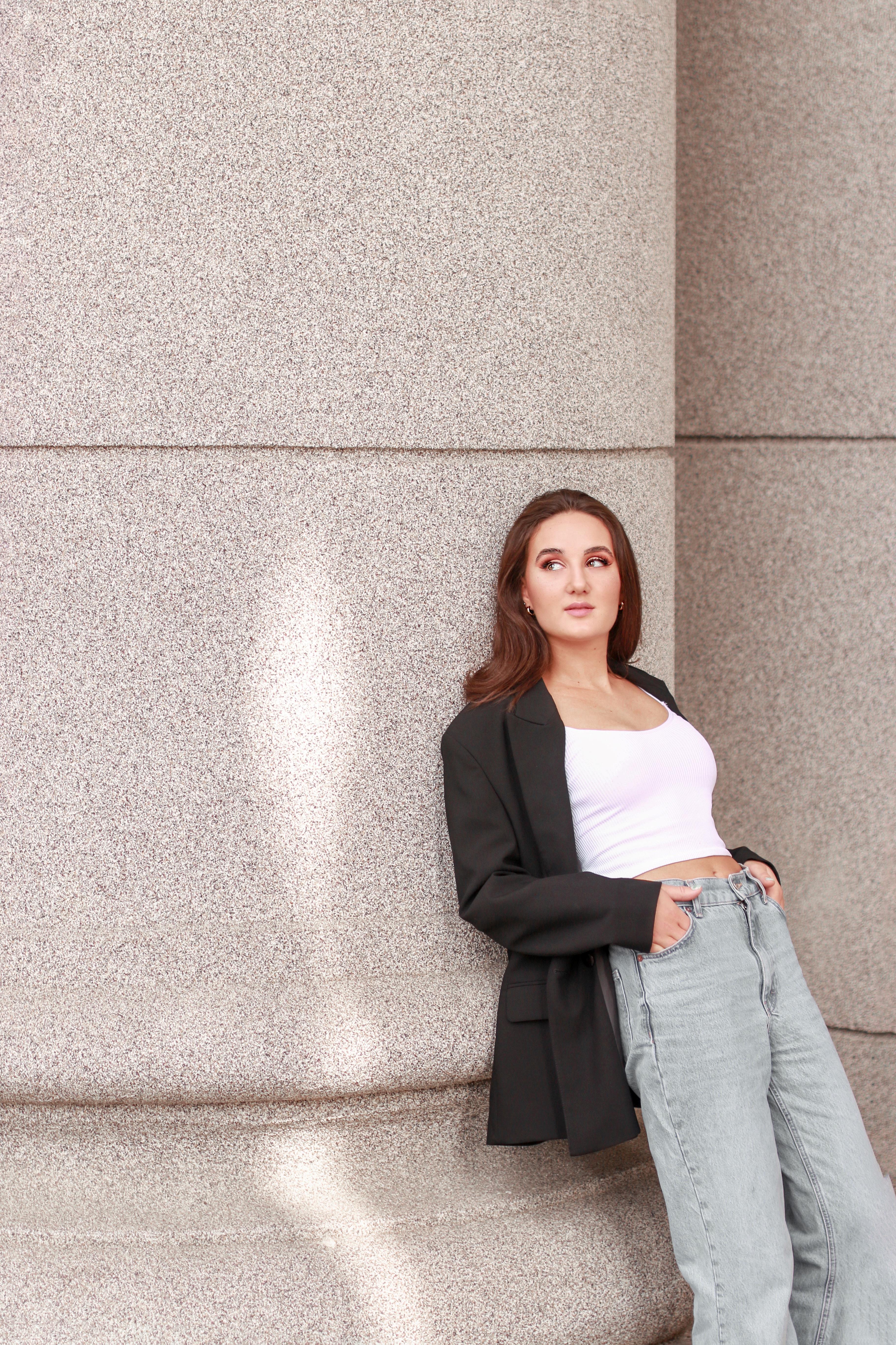 Woman in sweatsuit sitting on plant against wood wall