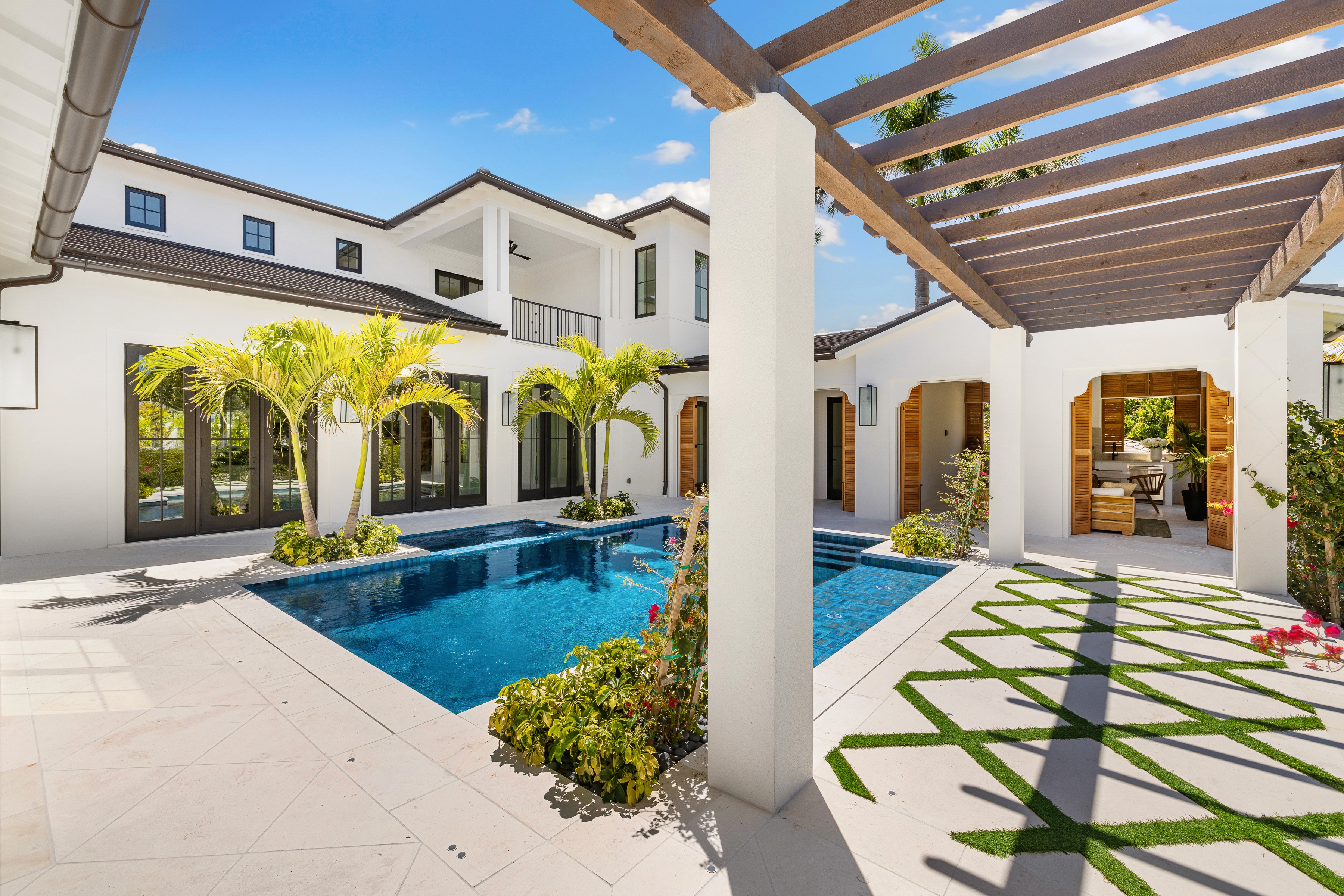 a west-indies styled pool and walkway with palm trees shown in the courtyard and wooden slats overhead