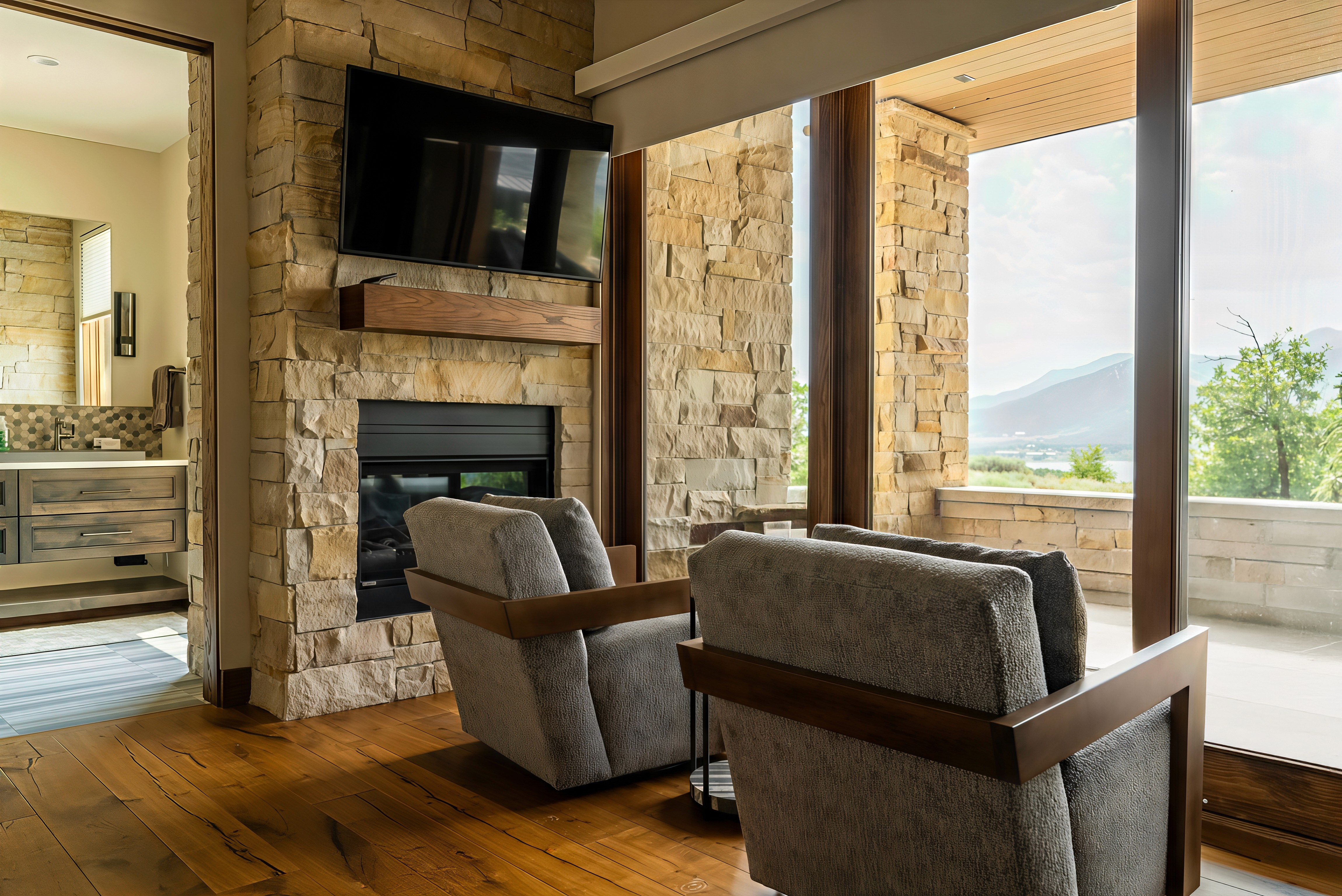 A spacious industrial-style interior with exposed brick walls, large windows, and natural light pouring in during sunset. Wooden desks with plants and workspace materials are arranged along the walls, with a view of greenery and an outdoor seating area.