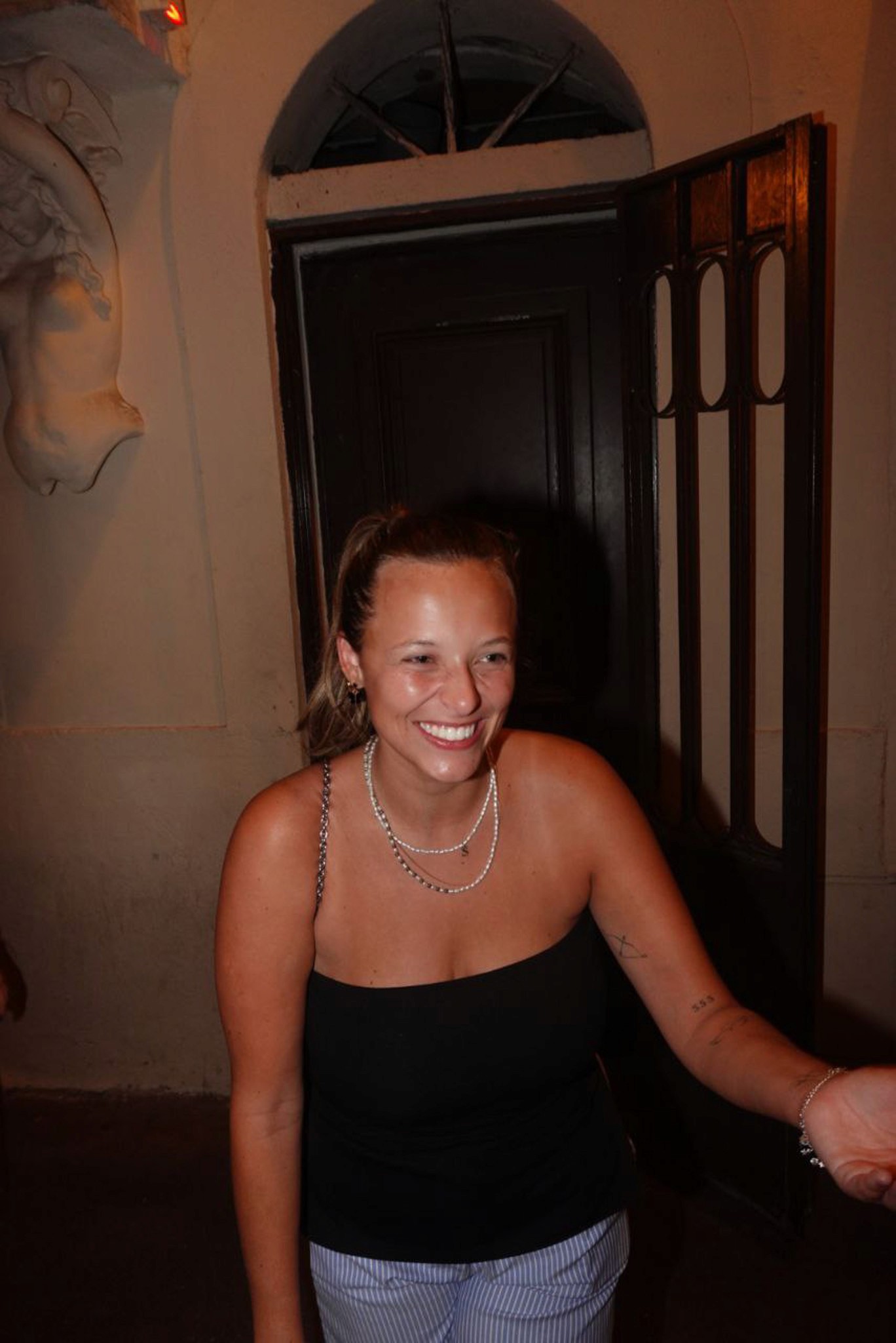 A solo traveler smiling and talking with new friends at night in Nice, surrounded by lively bars and warm street lights.
