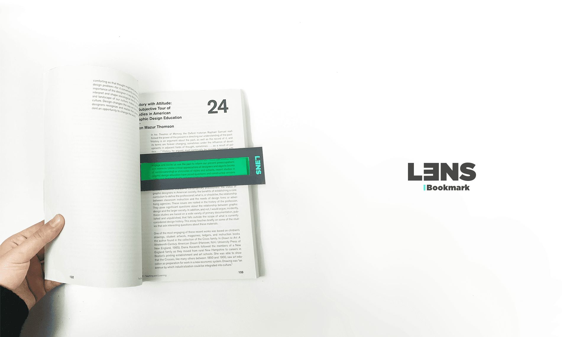 A hand holds open a book displaying page 24. The book’s pages contain text and images, including a green rectangular section with text. A black rectangular strip with “LENS” text is positioned across the open pages. The word “Bookmark” appears to the right of the strip. The background is white, and the word “LENS” is displayed vertically in black text.
