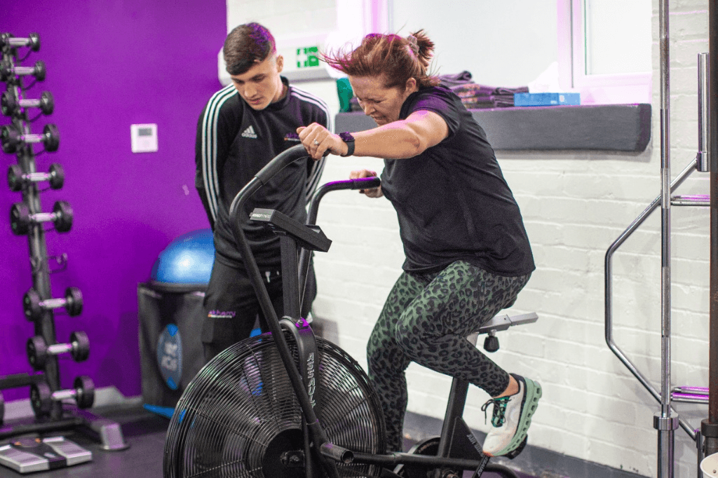 A woman performing high-intensity exercise on an air bike to help regulate cortisol levels.