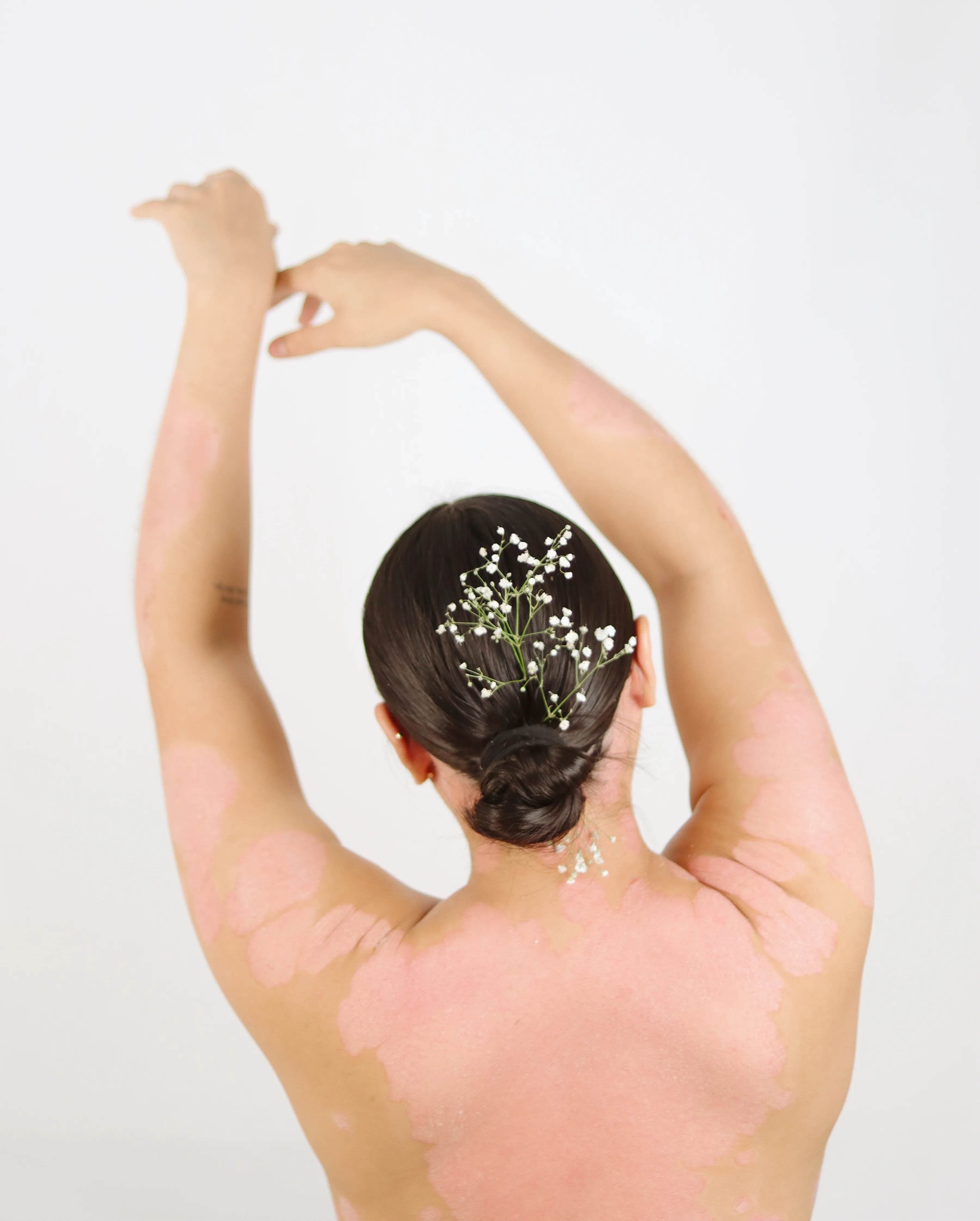 Mujer levantando los brazos con flores en el cabello