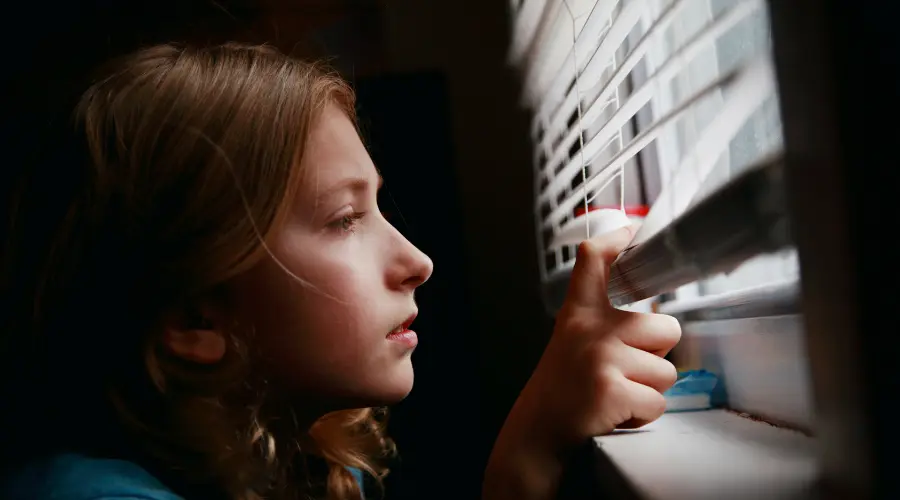 bambina che guarda fuori dalla finestra simbolo della dipendenza tecnologica nei bambini e adolescenti