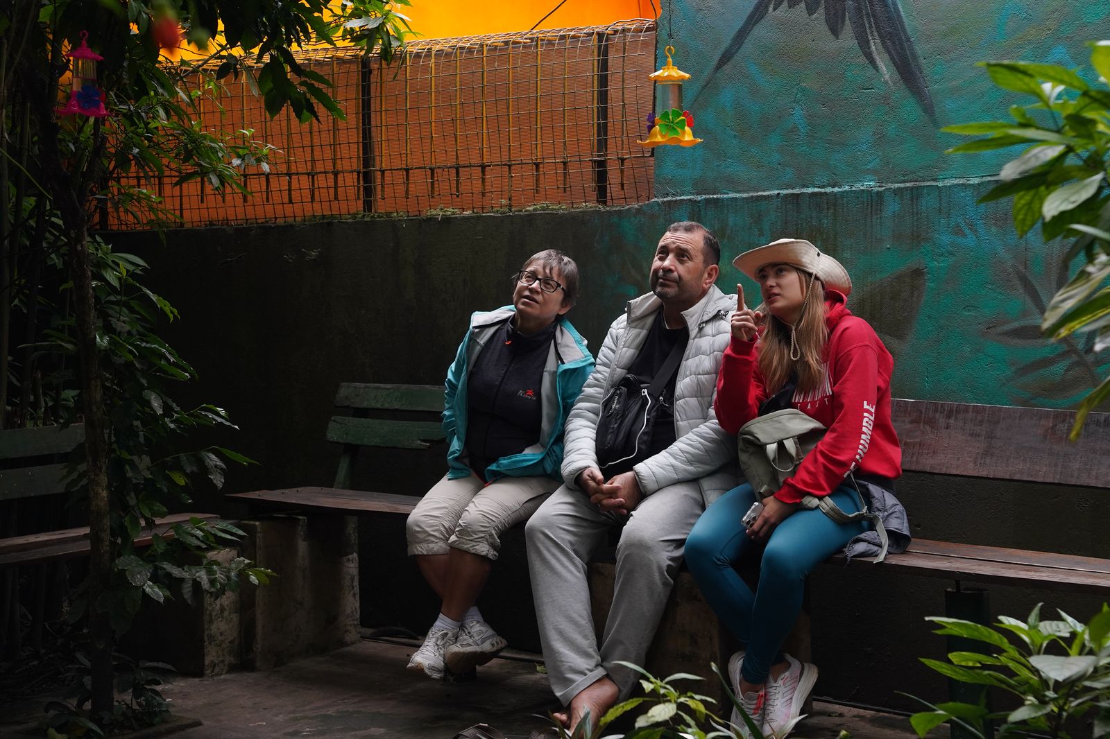 Mujer sentada sobre un tronco frente a una cascada doble en un bosque frondoso de Argentina.
