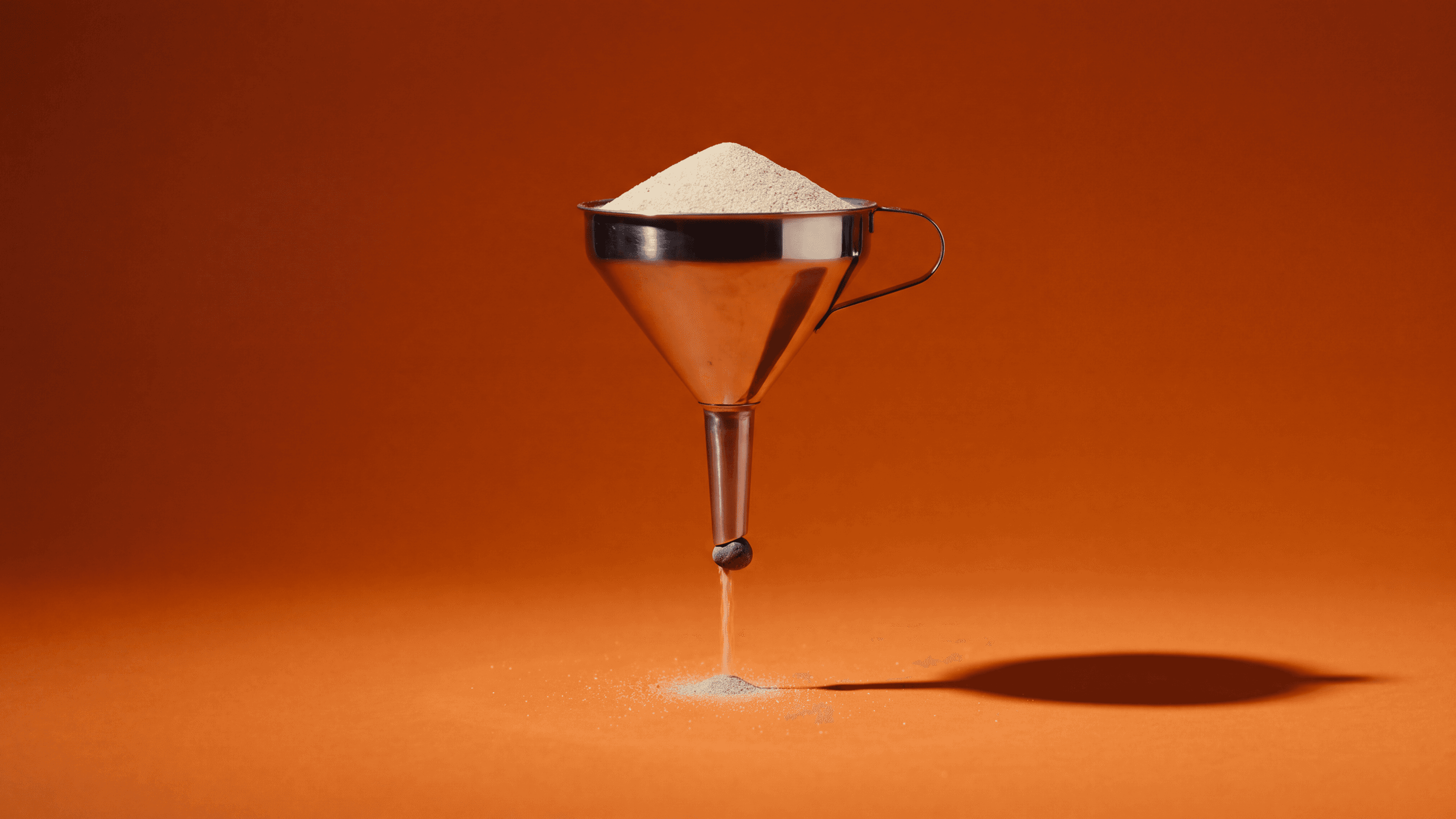 Metal funnel directs sand toward a single point, representing the conversion optimization process.