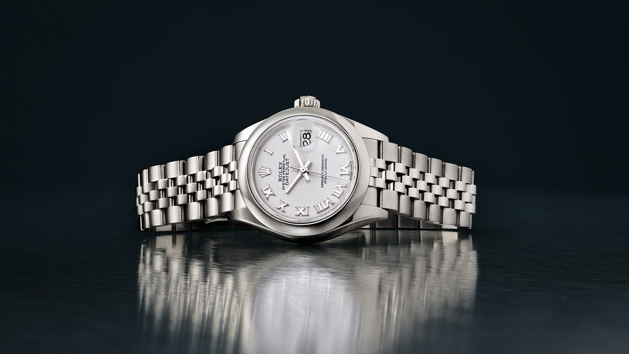 A silver Rolex wristwatch with a round face and metal band, displayed against a dark background.