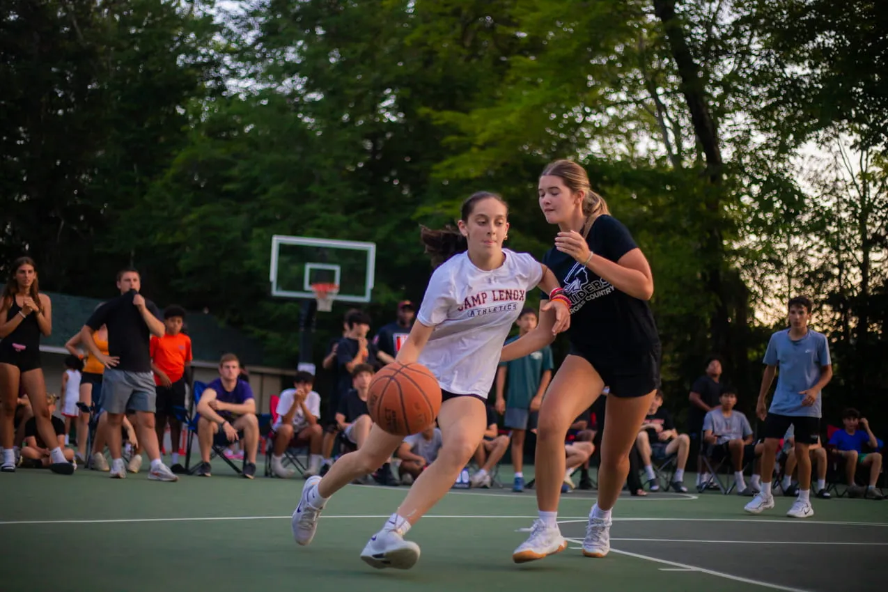 Campers playing a basketball game on the outdoor court at Camp Lenox