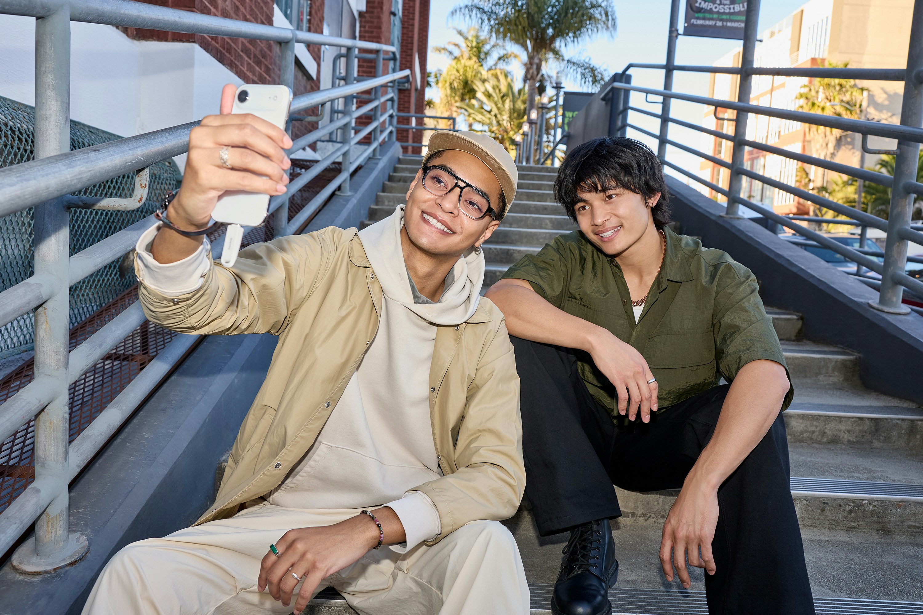 Two young men taking a selfie on outdoor stairs.
