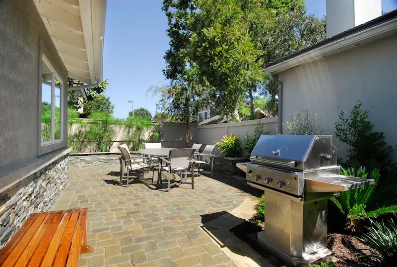 Flagstone patio and BBQ area. Modern kitchen with wooden cabinetry, stainless steel appliances, and granite countertops. Irvine Transitional Modern. Photo by Chris Darnall.