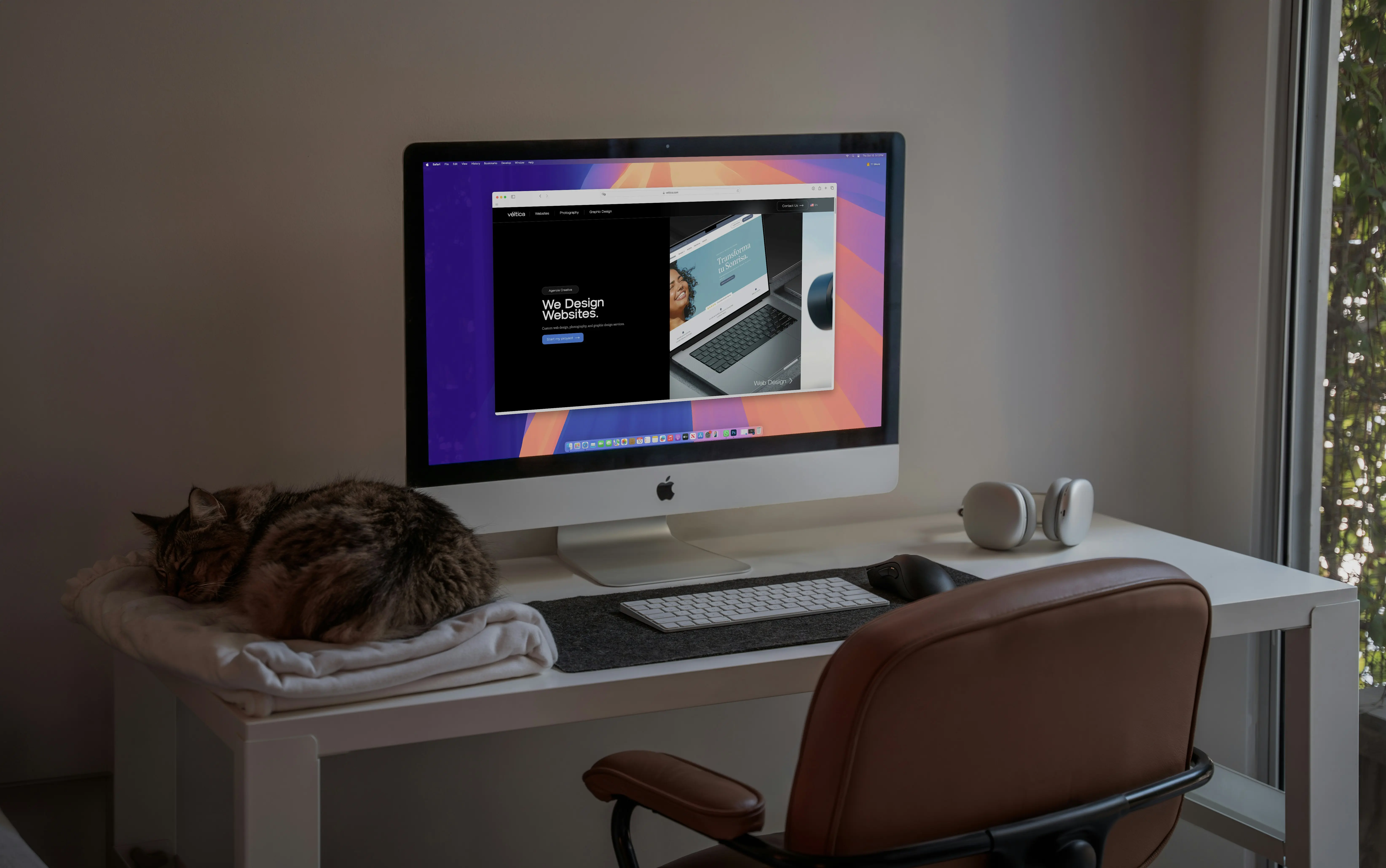 Cozy home workspace with computer, cat and web design project on screen