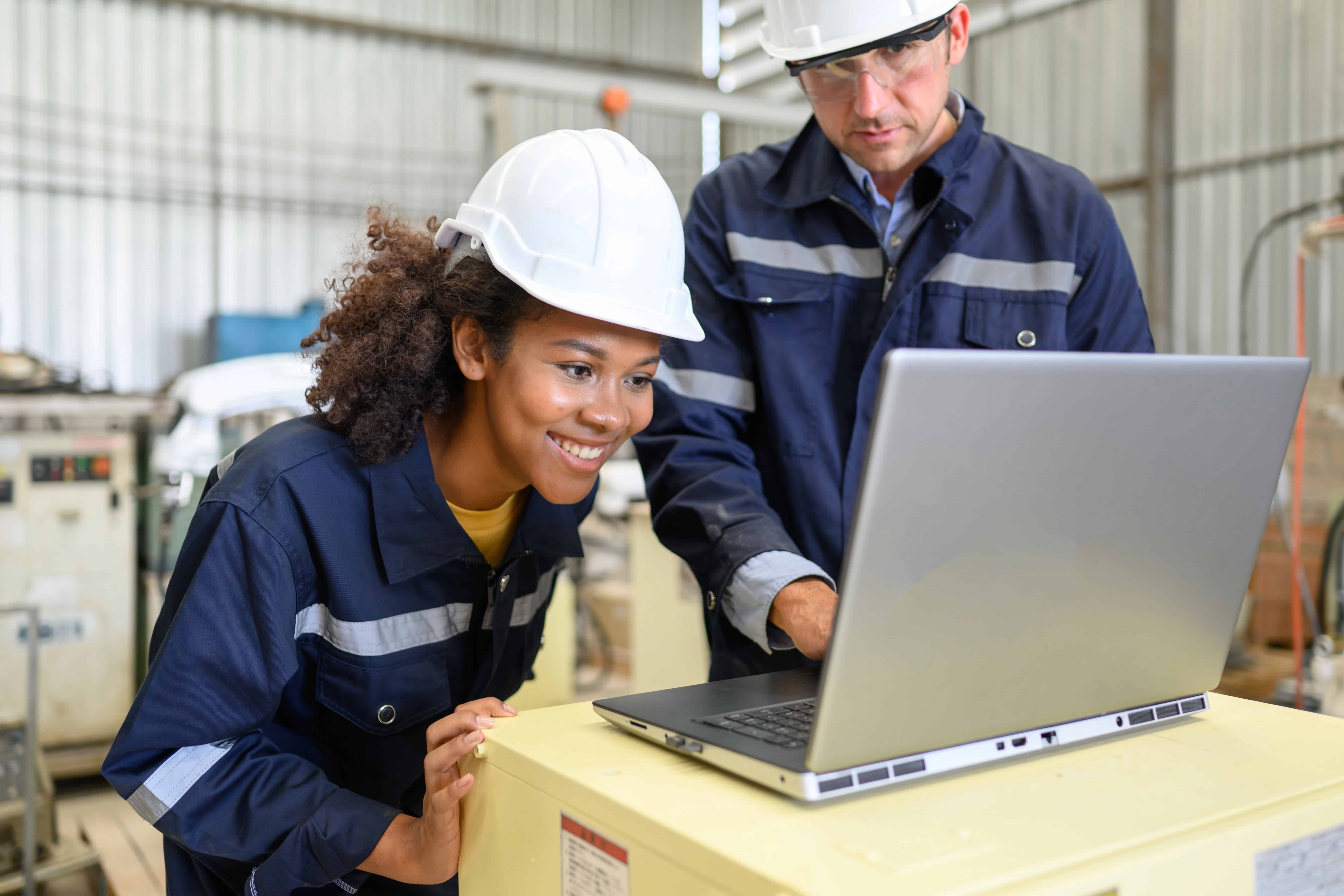 Female engineer in manufacturing facility working with colleague and enjoying good wellbeing