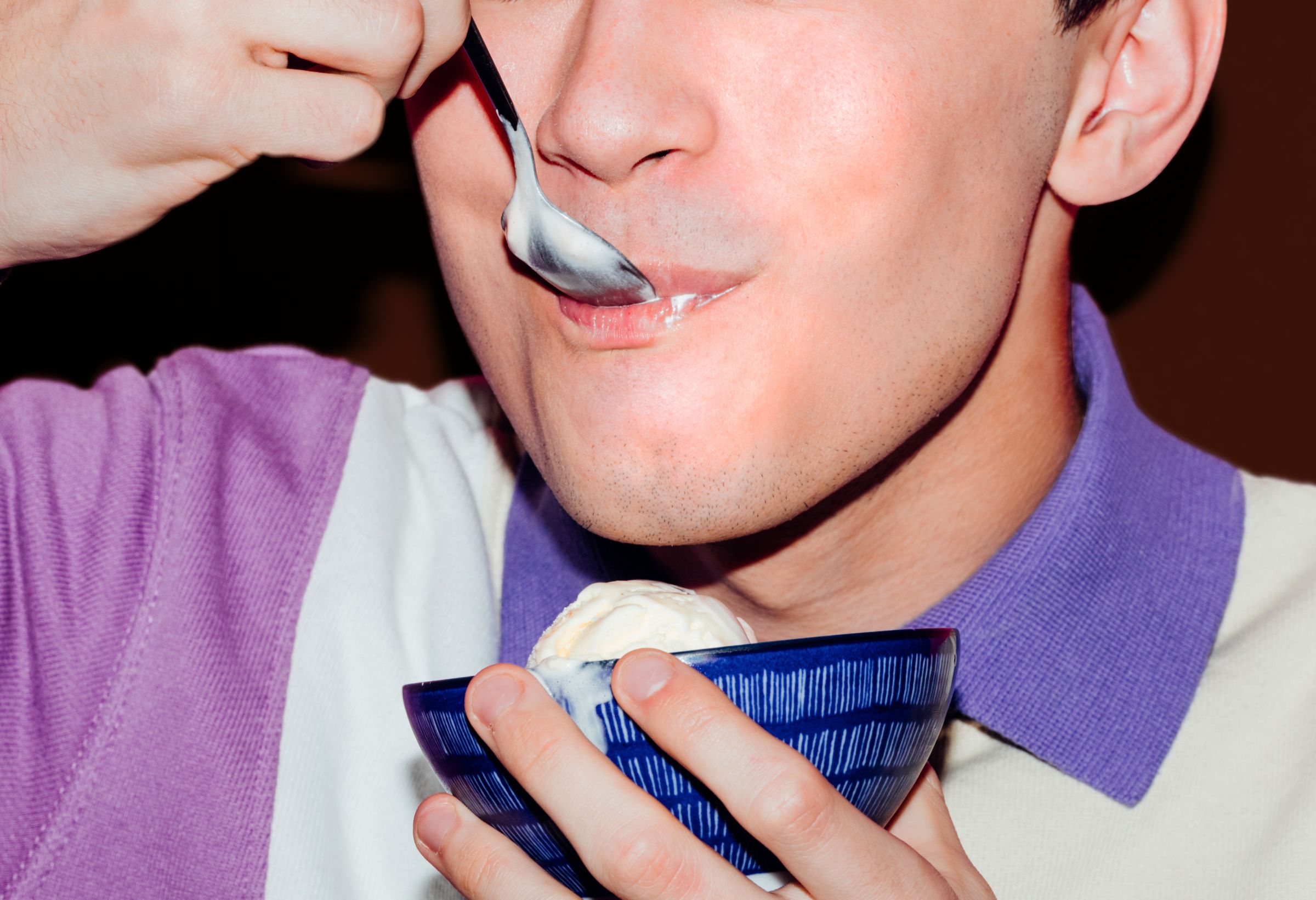 Close-up of a person enjoying ice cream, spoon in mouth with a satisfied expression, conveying the ease and enjoyment of finding allergen-friendly options with Edible.