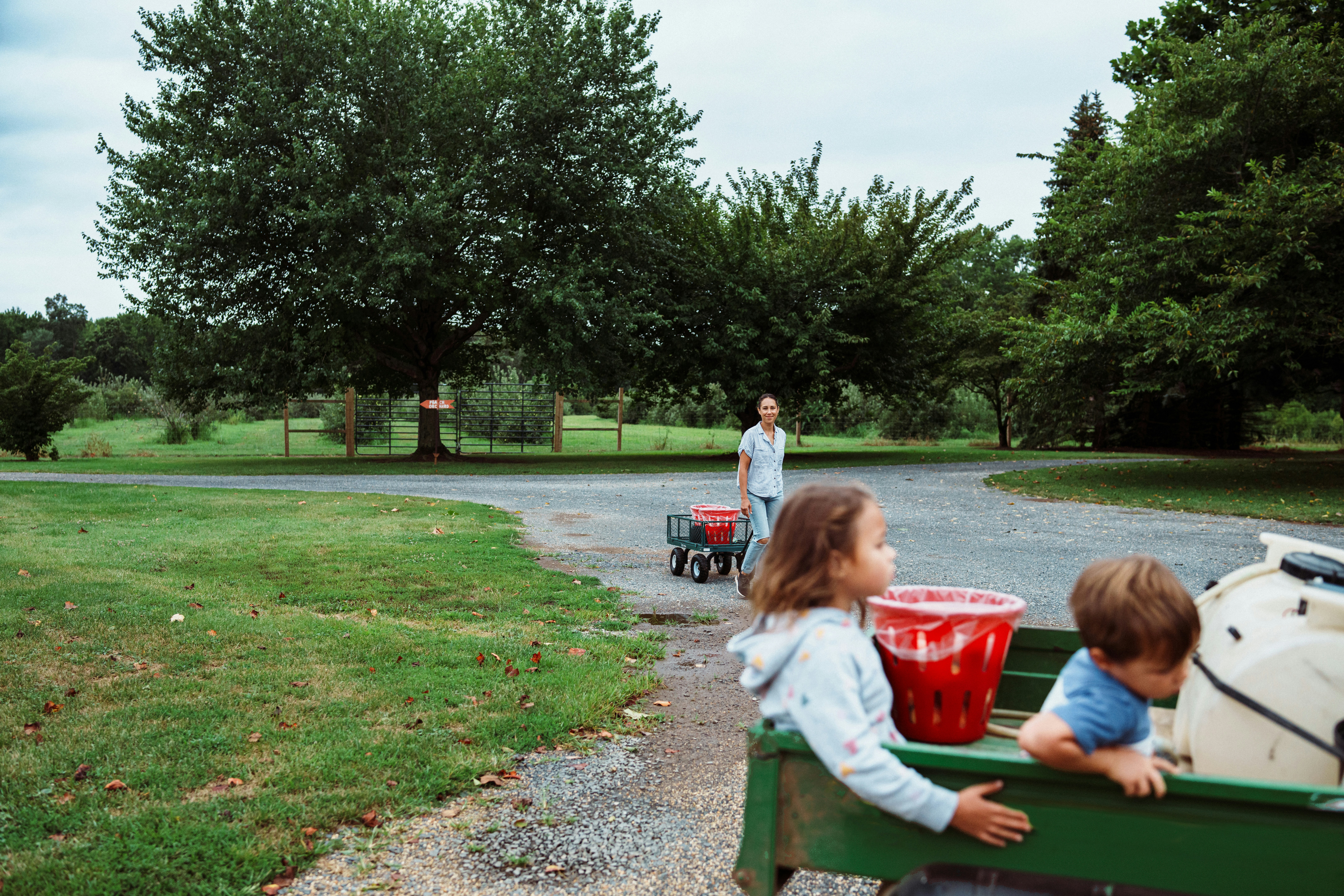 Children riding in a wagon with red buckets