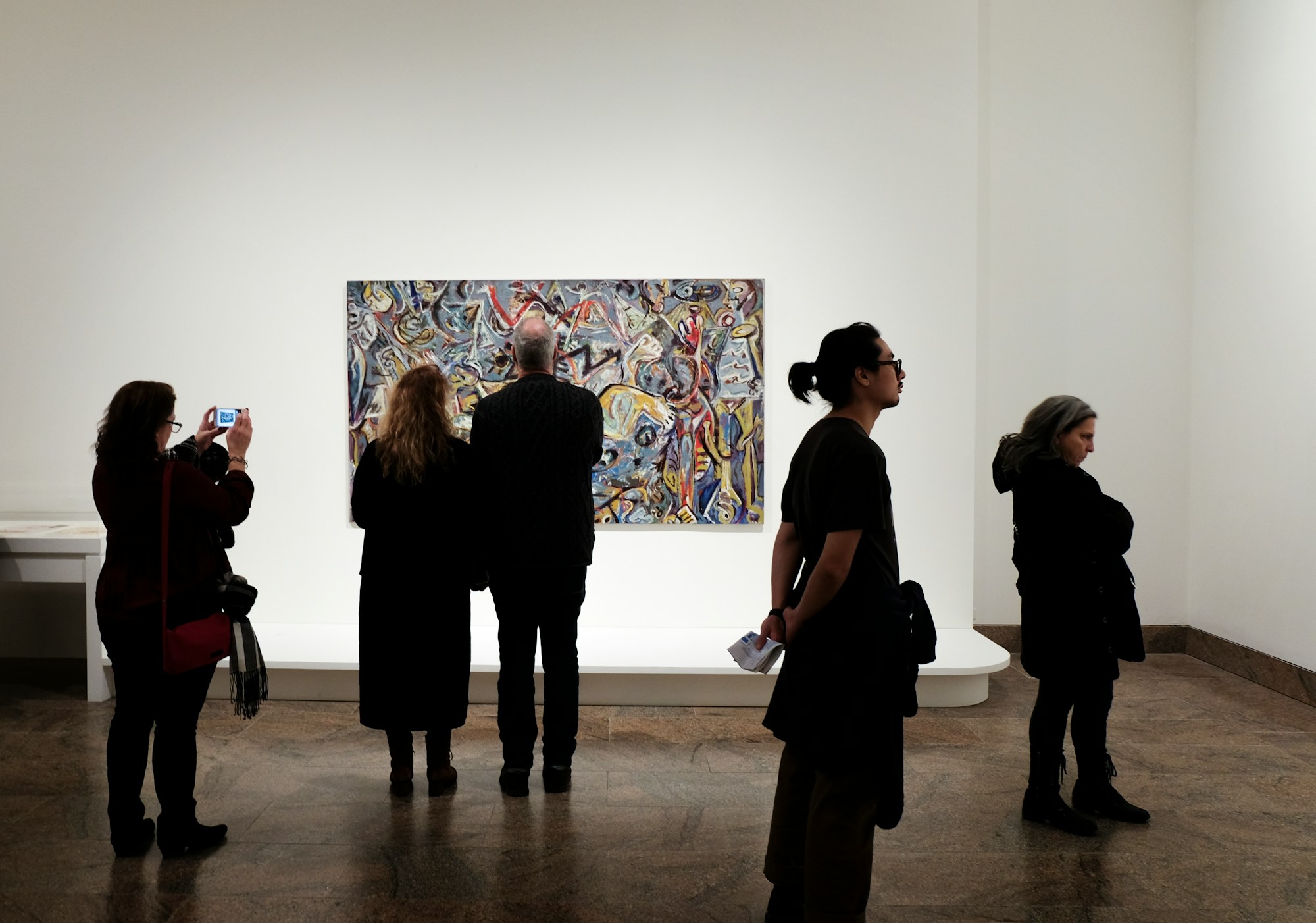 Visitors looking at a large colourful painting in a white gallery
