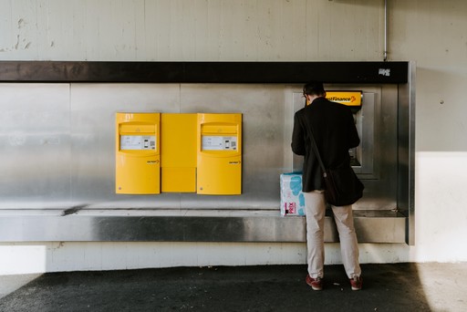 A person stands in front of a yellow vending machine in a modern, minimalist interior space.