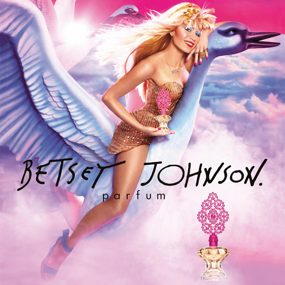 Betsey Johnson Parfum Kampagnenmotiv – Frau im goldenen Minikleid reitet auf einem überlebensgroßen Schwan durch rosa Wolken, im Vordergrund der Parfumflakon mit pinker, perlenbesetzter Krone, darunter handschriftlicher Schriftzug „Betsey Johnson. parfum".