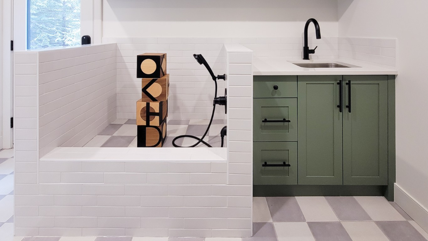 Image of KHD Homes bathroom design with green cabinets, white tile and black fixtures in a luxurious setting.