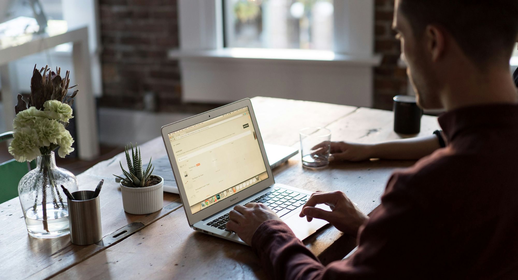 homem de camisa longa numa mesa utilizando um notebook