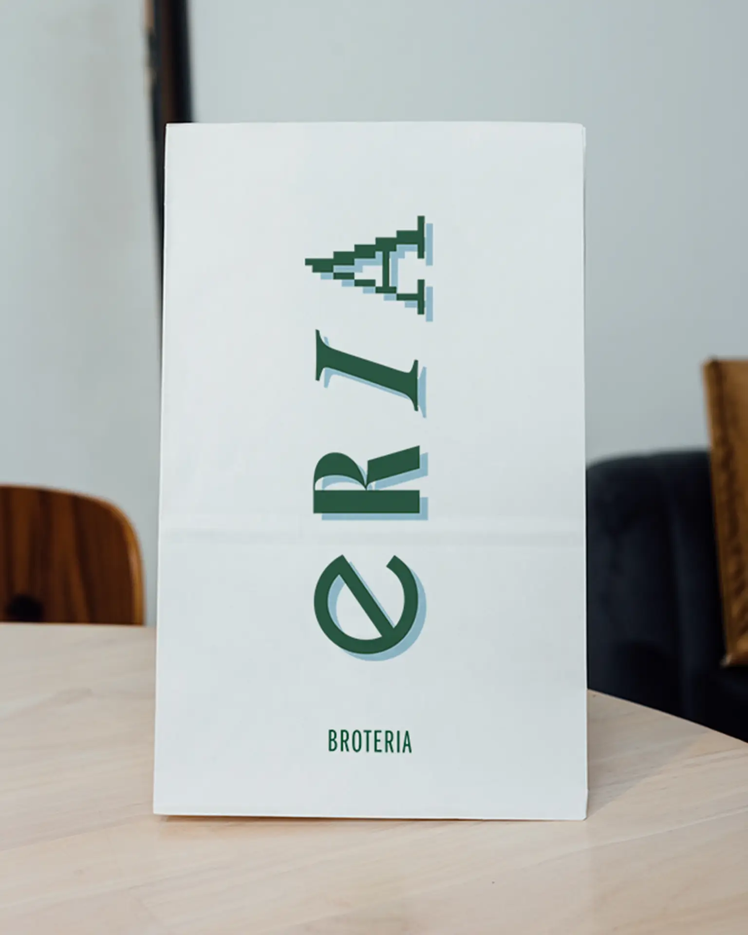White Broteria bread bag with green stacked logo symbols on a café table