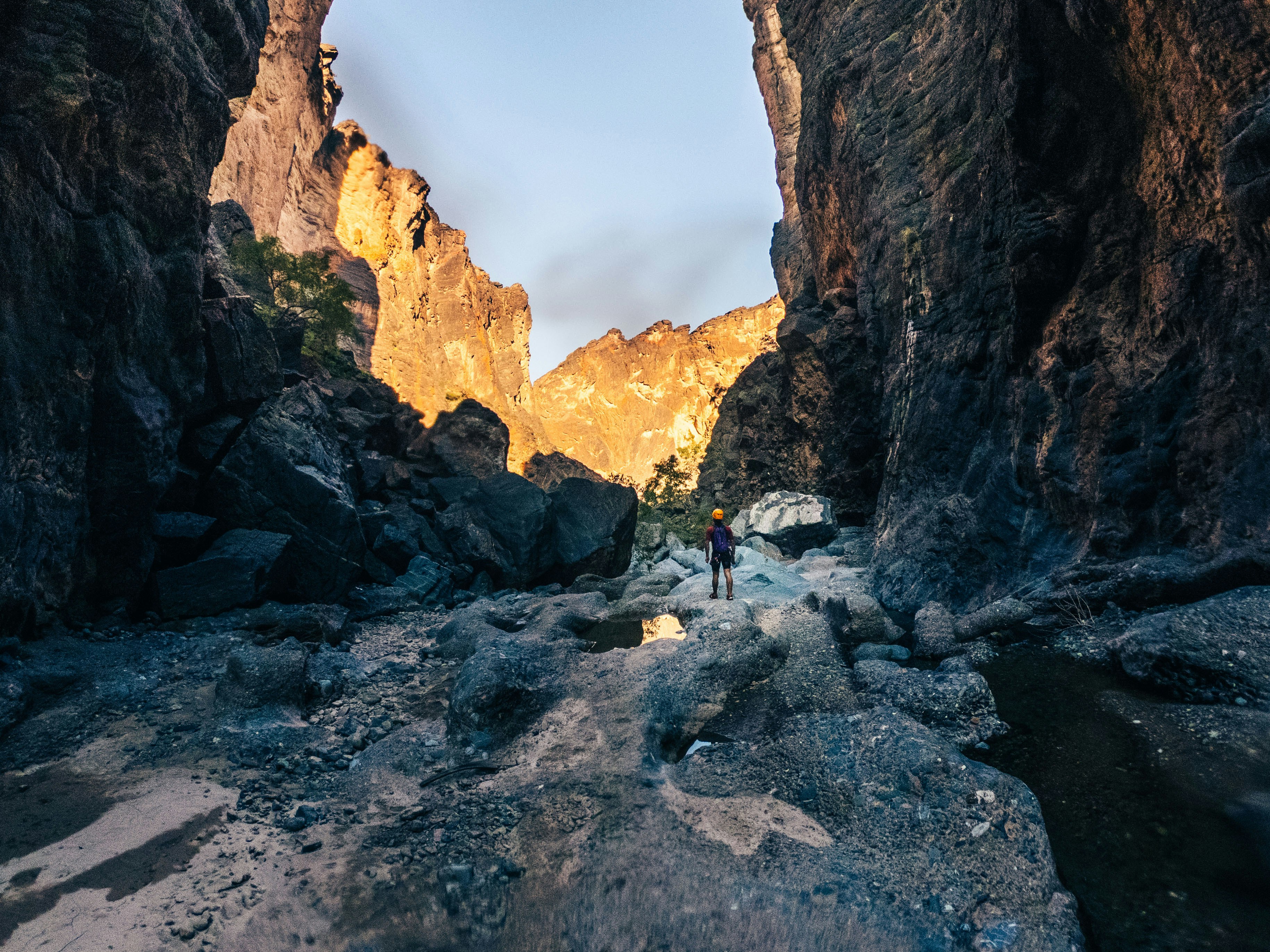 person in blue jacket standing on rocky mountain during daytime