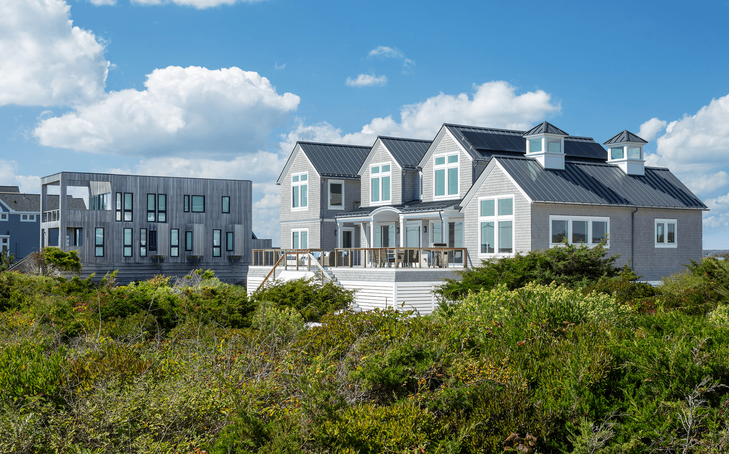 A large, multi-story house with a wraparound porch, set against a twilight sky and surrounded by greenery.