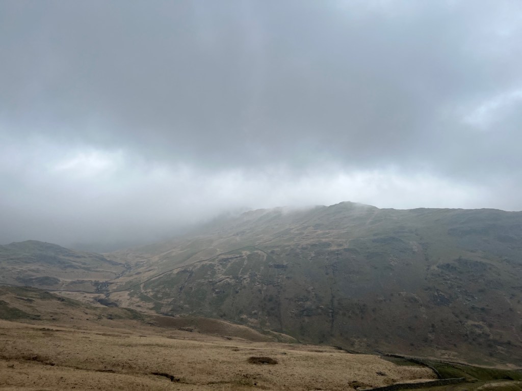 Fog can be seen coming over the fells towards us. Thick cloud hides the peaks in the distance.