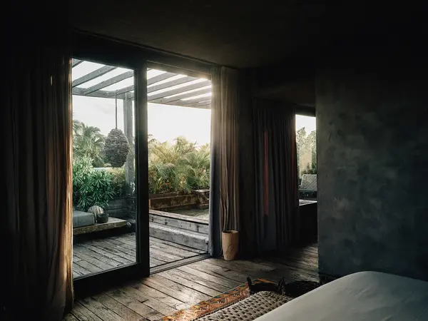 Aire Suite at Nômade Tulum featuring majestic sunlight on private terrace, large glass window, and hanging lamp.